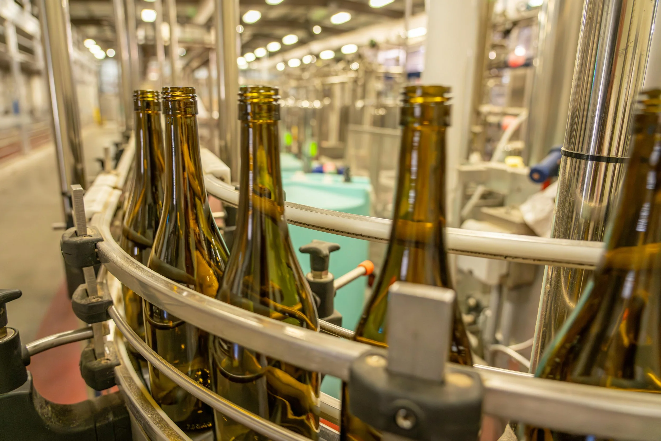 Production line with brown glass bottles moving on a conveyor belt in a factory.