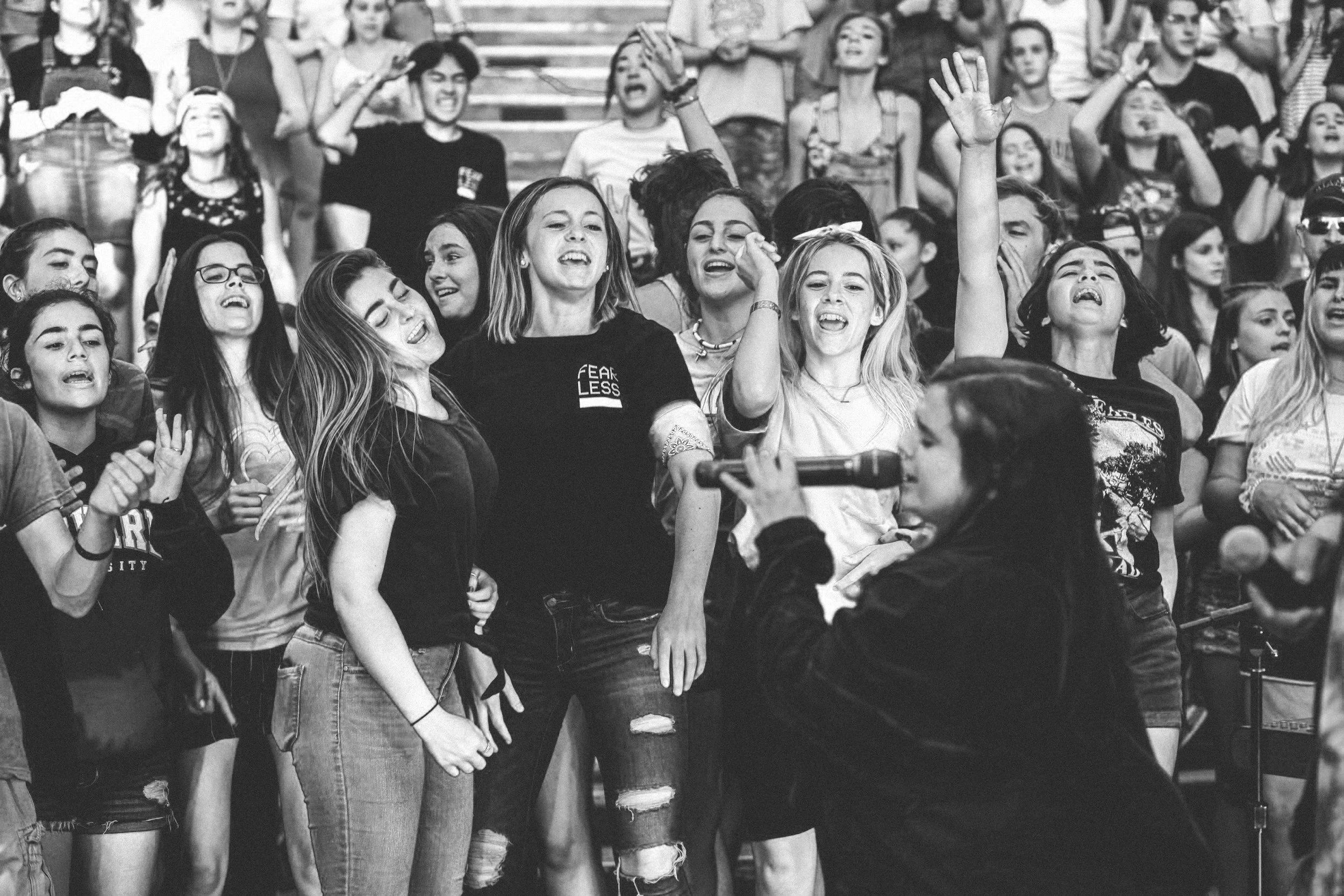 Un gruppo di giovani mentre canta e si diverte con un microfono in mano, in bianco e nero.