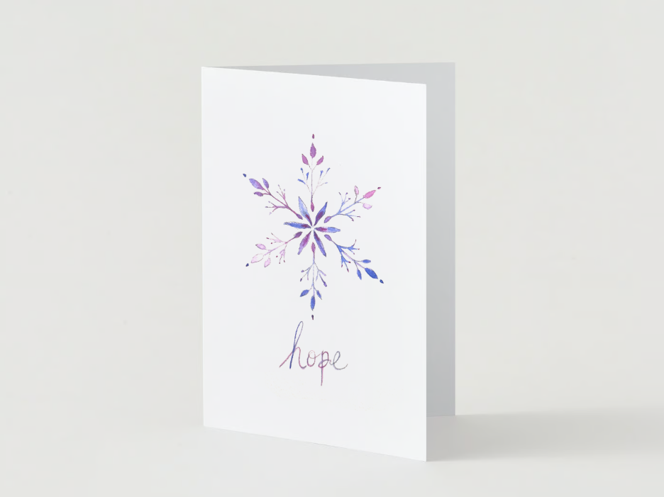 White greeting card with a watercolor snowflake design in purple and blue, and the word "hope" written below.