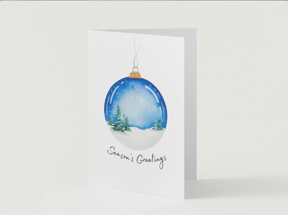 A holiday greeting card with a watercolor illustration of a snowy landscape inside a Christmas ornament, featuring pine trees and a starry sky, with the text 'Season's Greetings'.