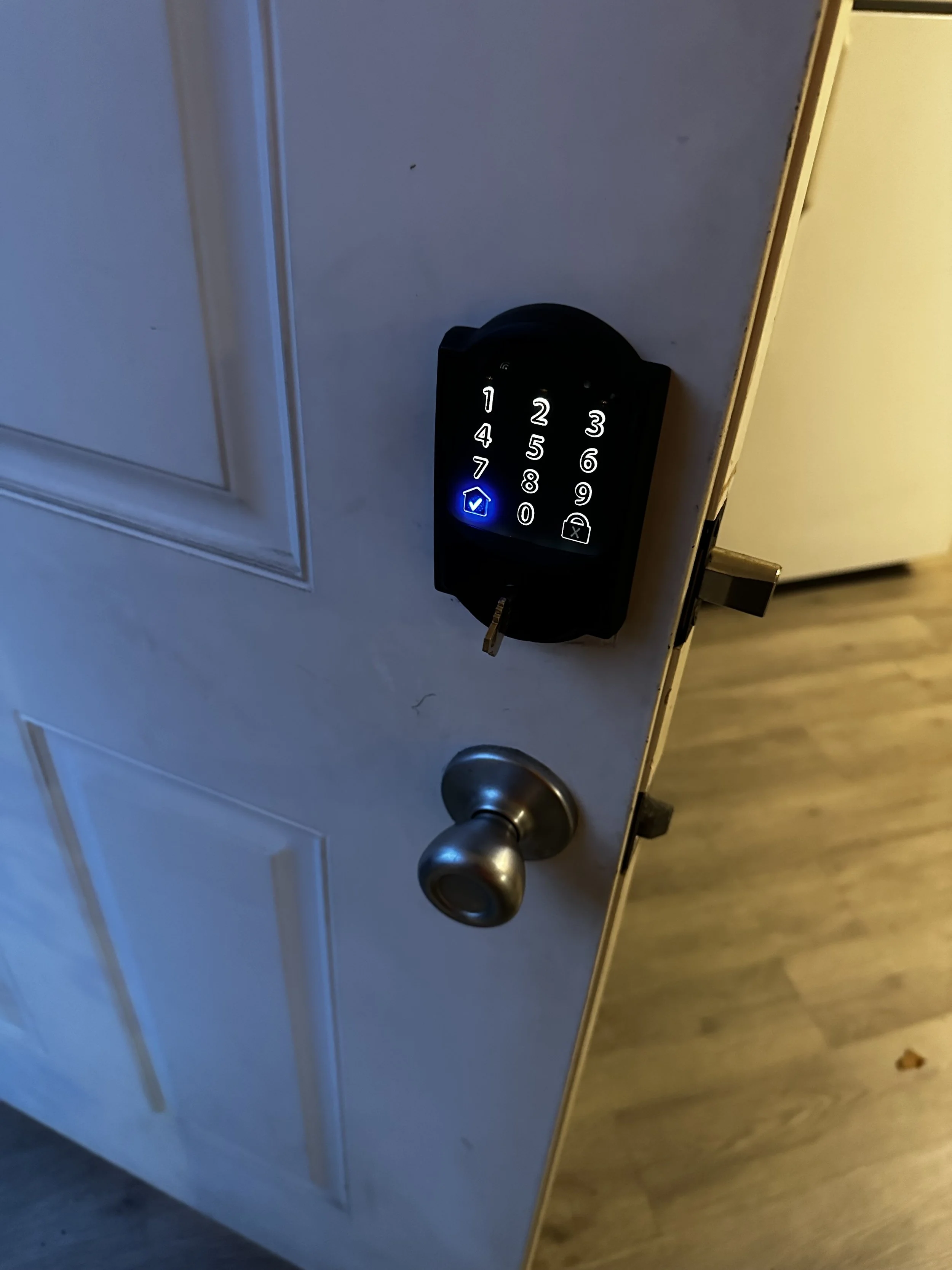 Door with a digital keypad lock showing the number 7 and a check mark, and a silver doorknob.
