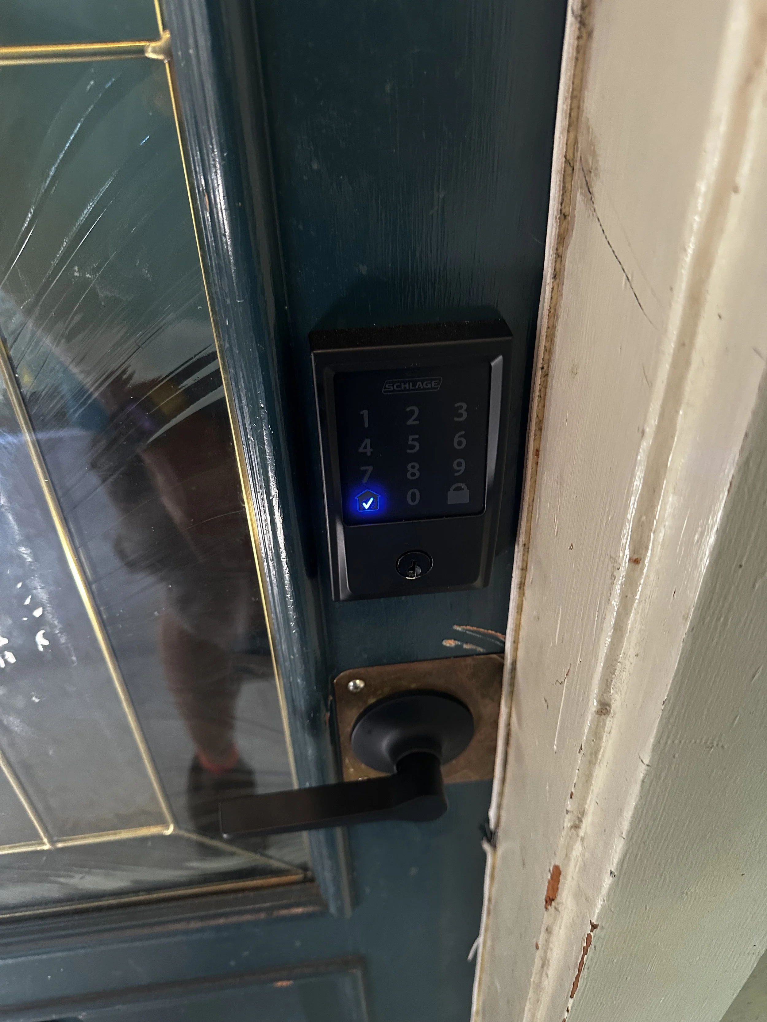 Door with a digital lock keypad with a blue light, a keyhole, and a black door handle.