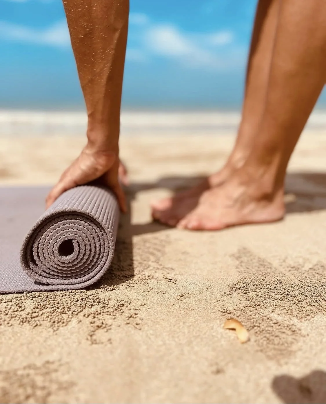 Rolling out a pilates mat on the beach