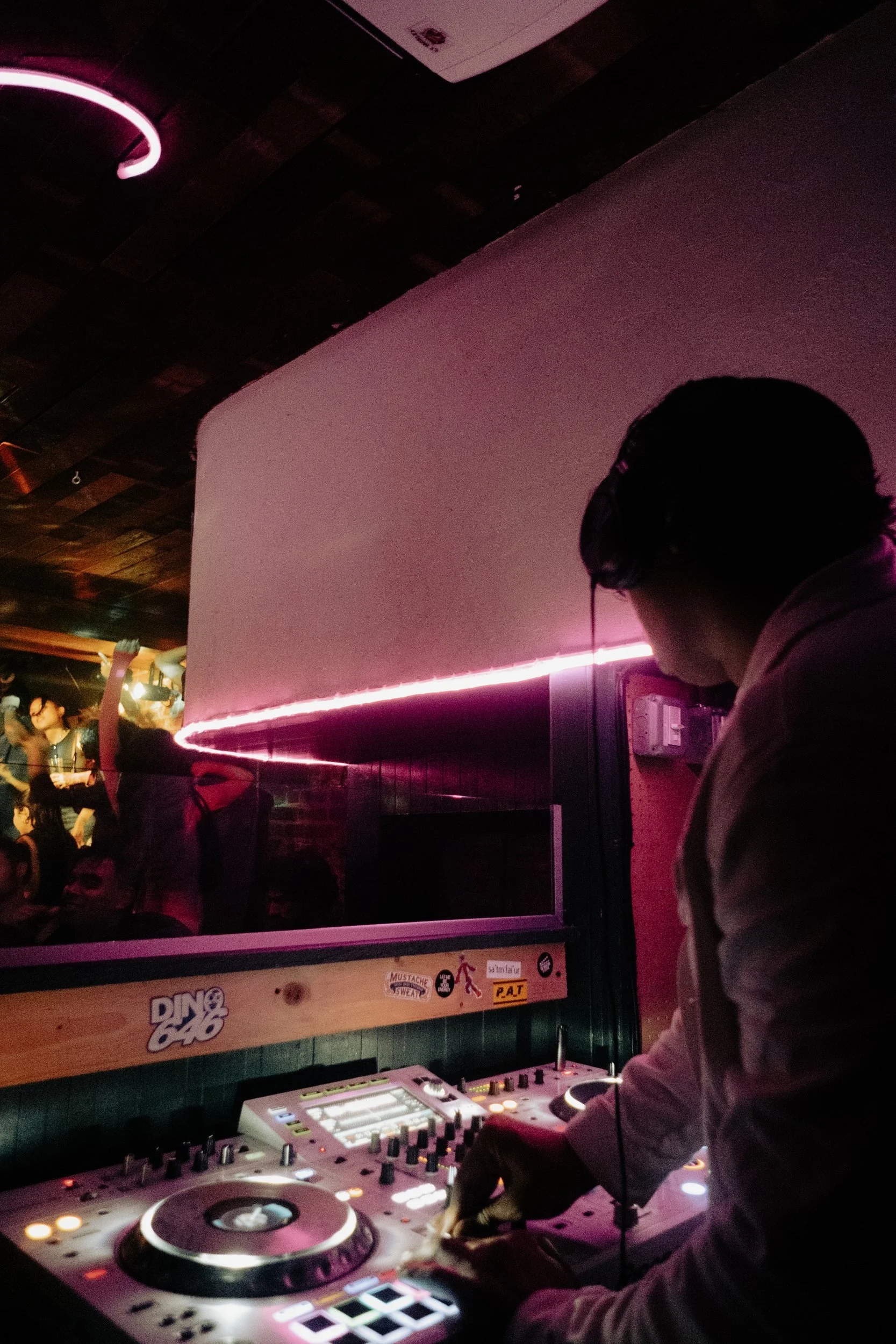 DJ at decks beneath magenta lighting