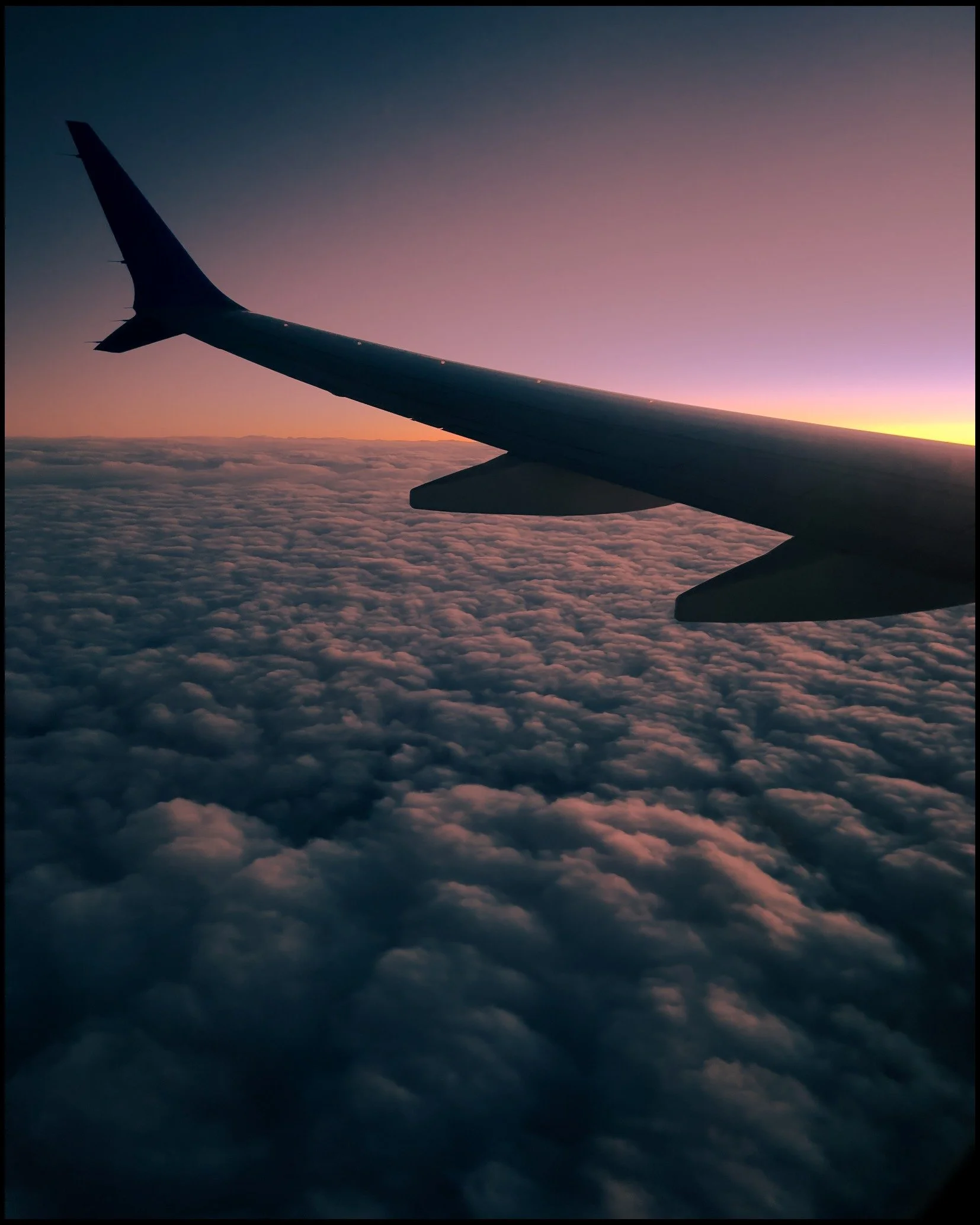 Airplane wing above clouds at dusk