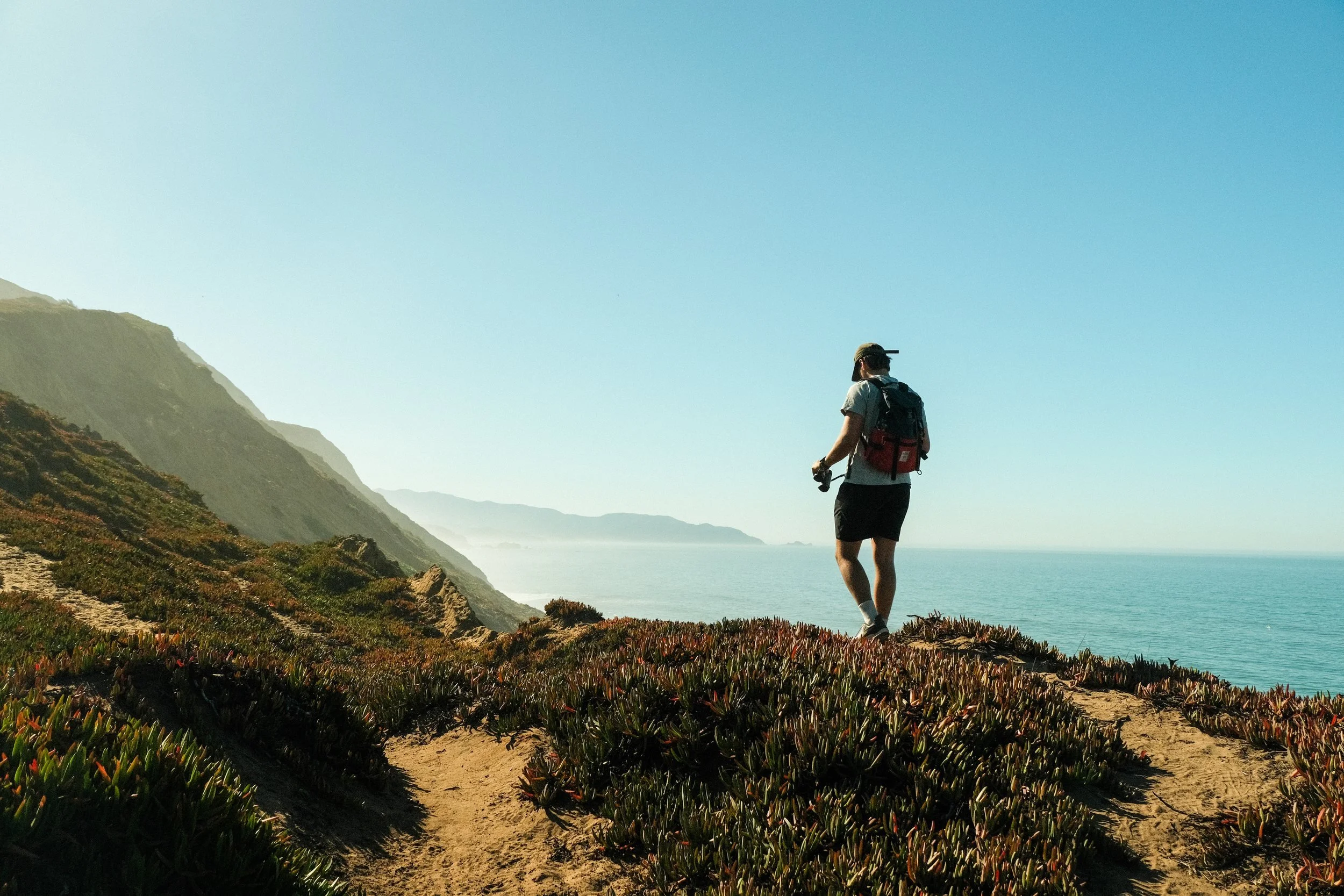 Hiker looking toward the ocean from a coastal trail