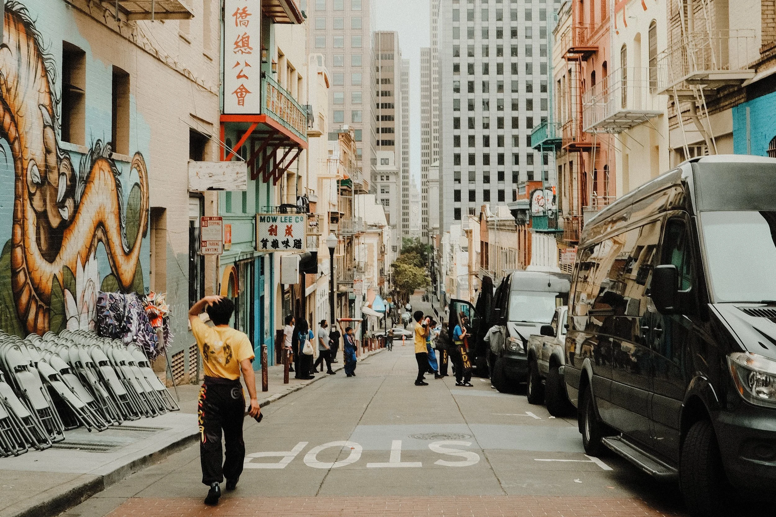 City street with pedestrians, murals, and parked vehicles
