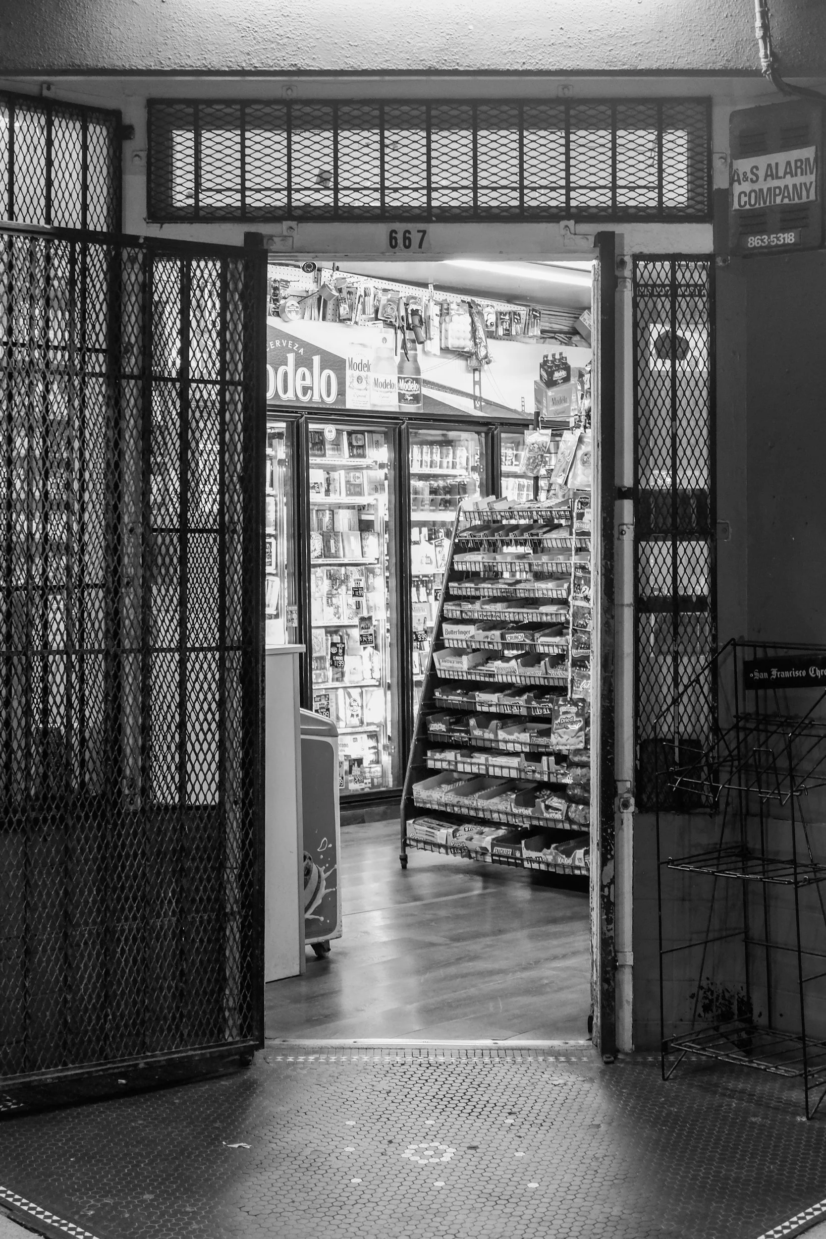 Black and white corner-store entrance framed by an open gate