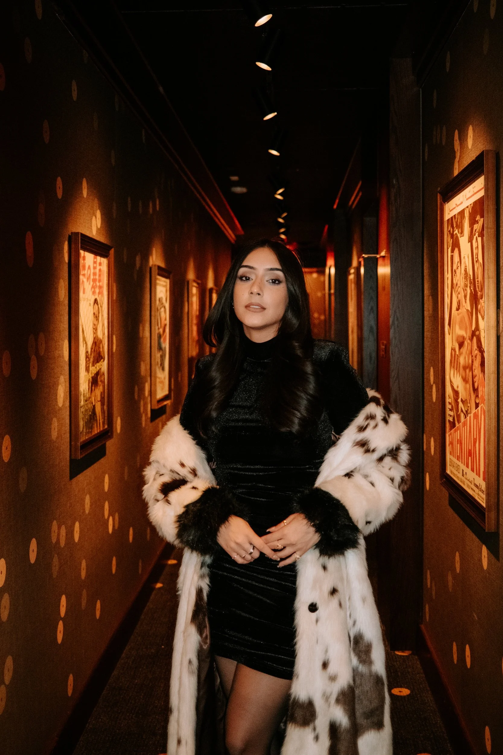 Full-length portrait in a warmly lit hallway