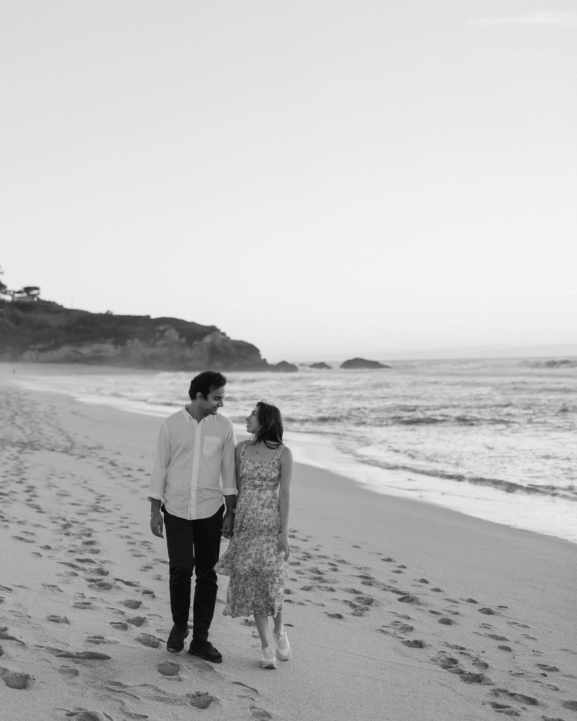 Black and white rear view of a couple walking on a beach