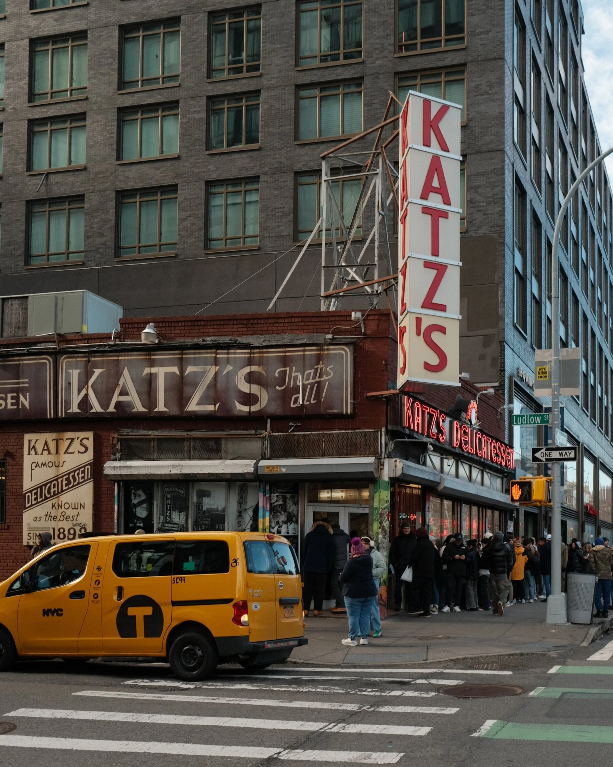 Yellow taxi passing Katzs Delicatessen