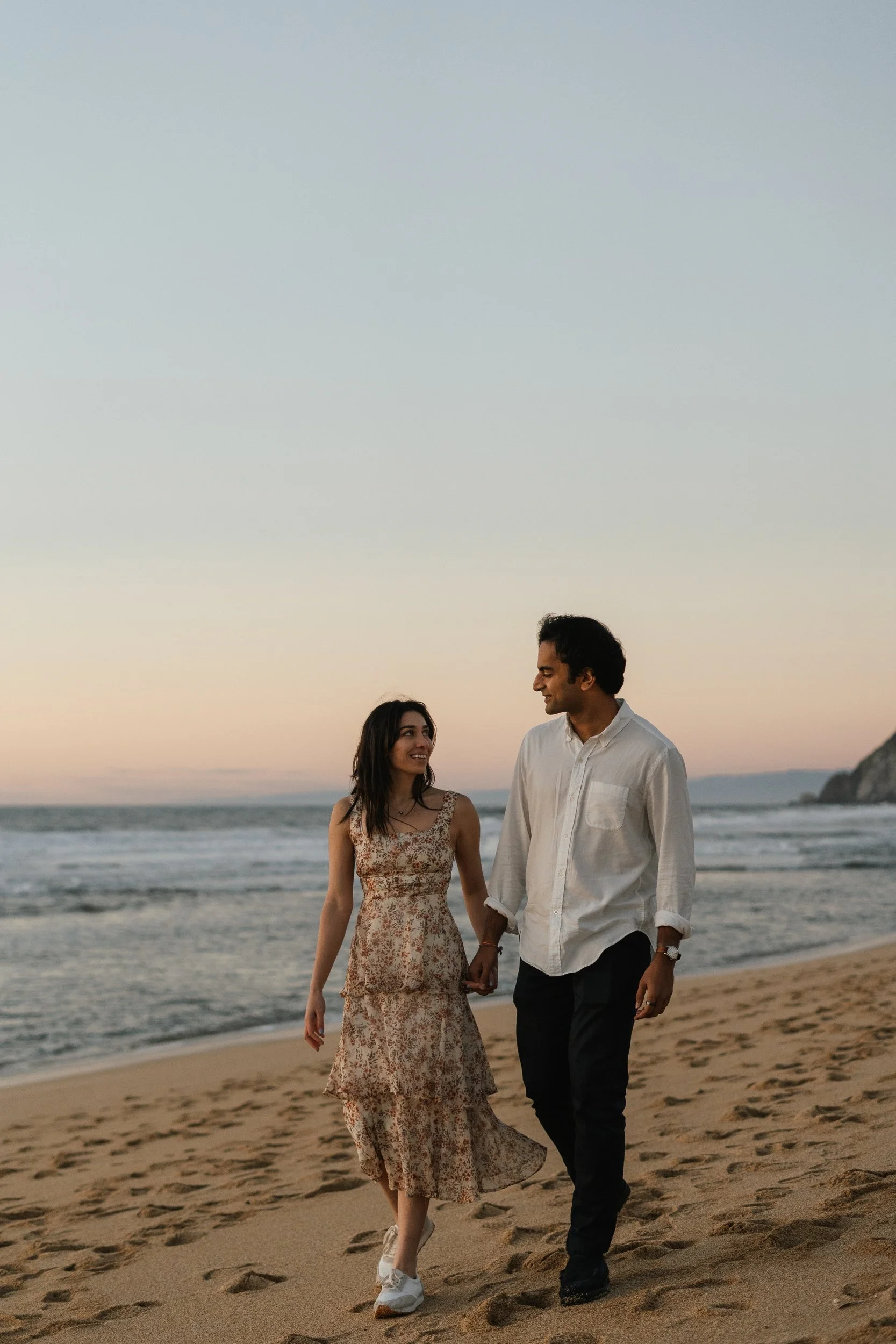 Couple walking along a beach at dusk