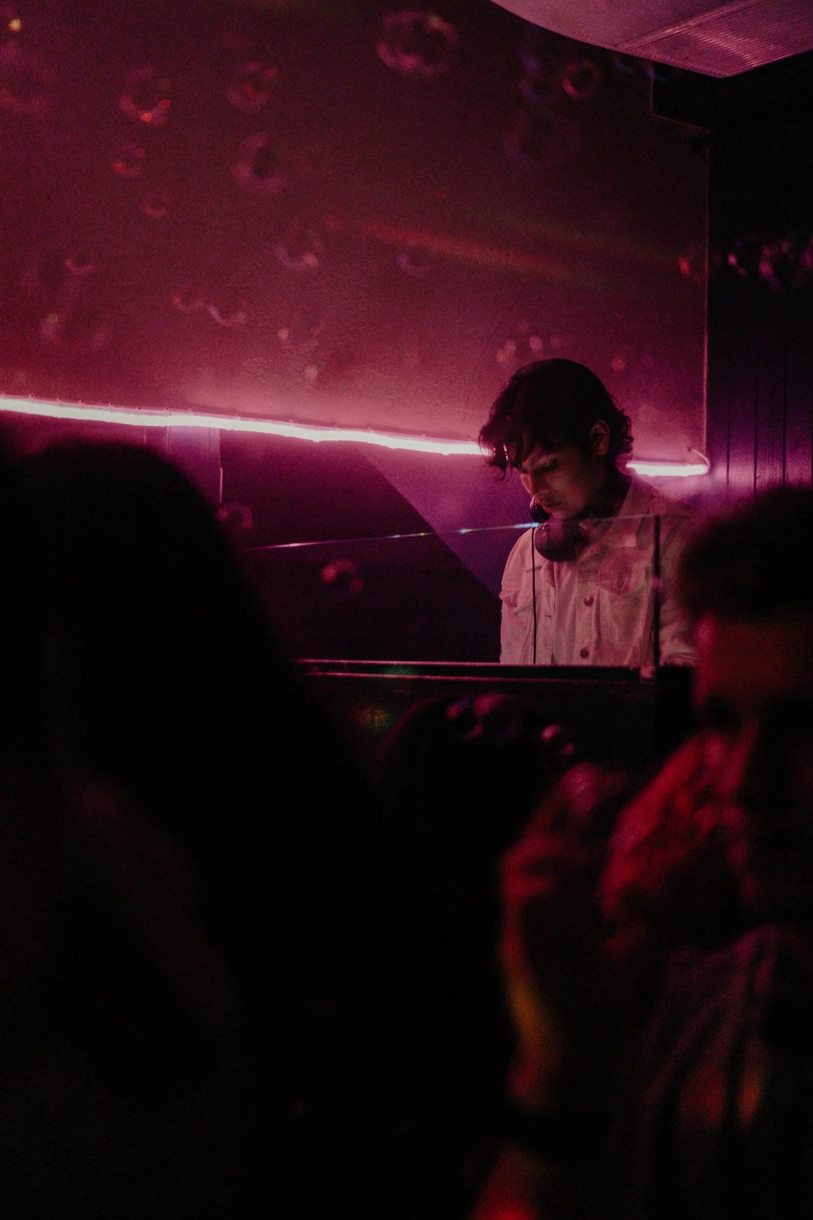 DJ performing beneath magenta lights