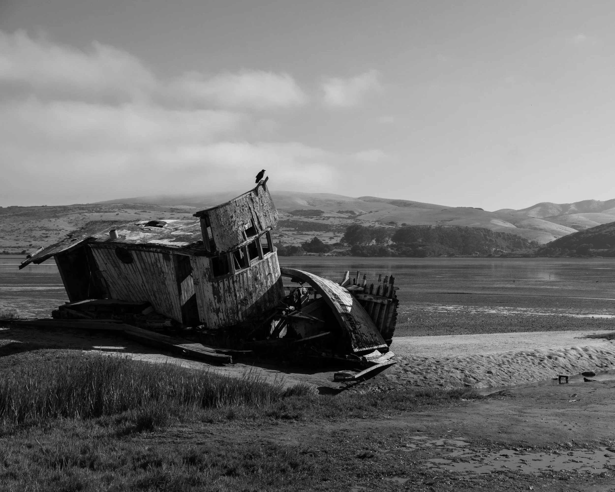 Black and white weathered boat beside an inlet
