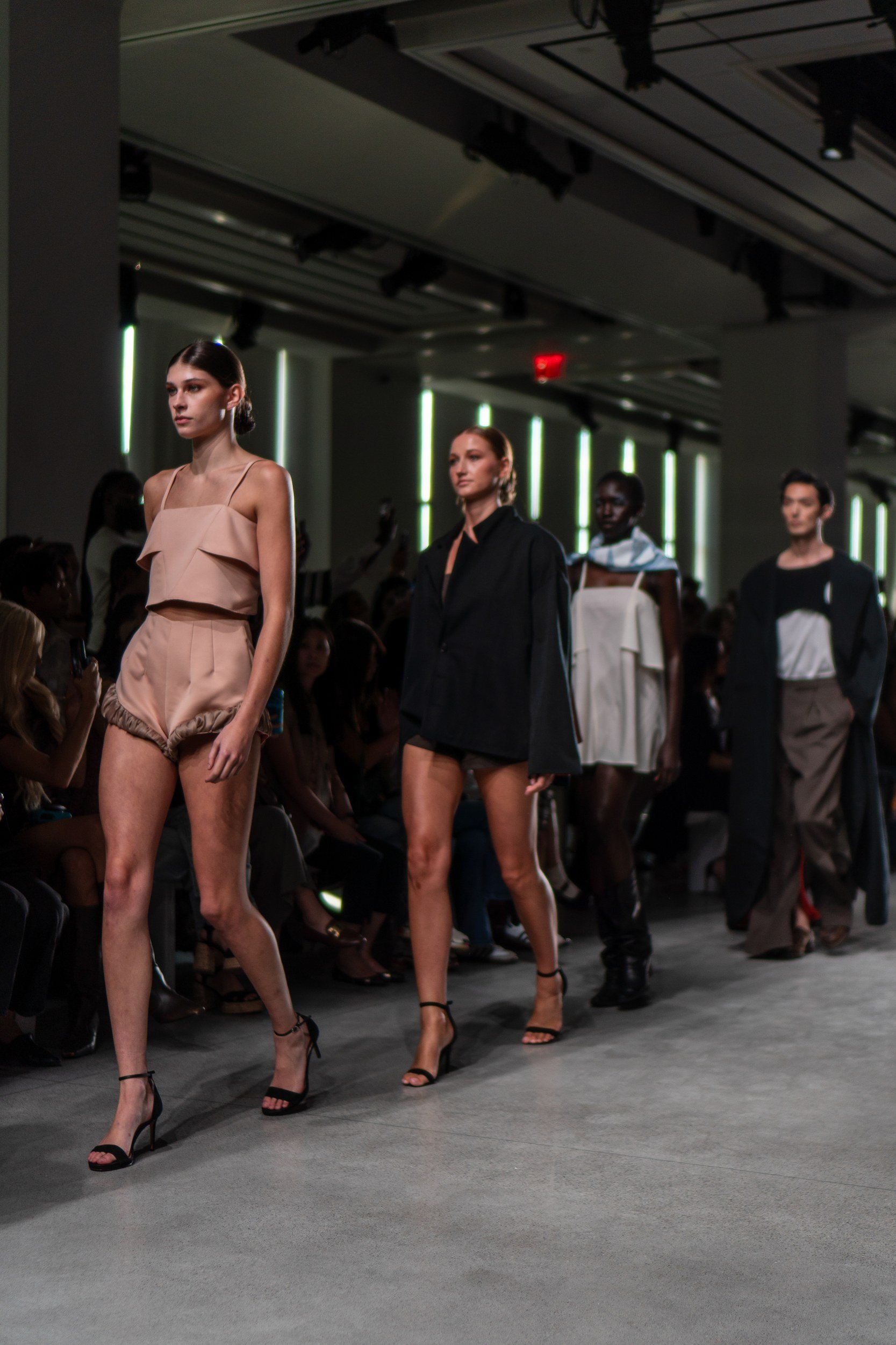 Models walking together toward the front of a runway