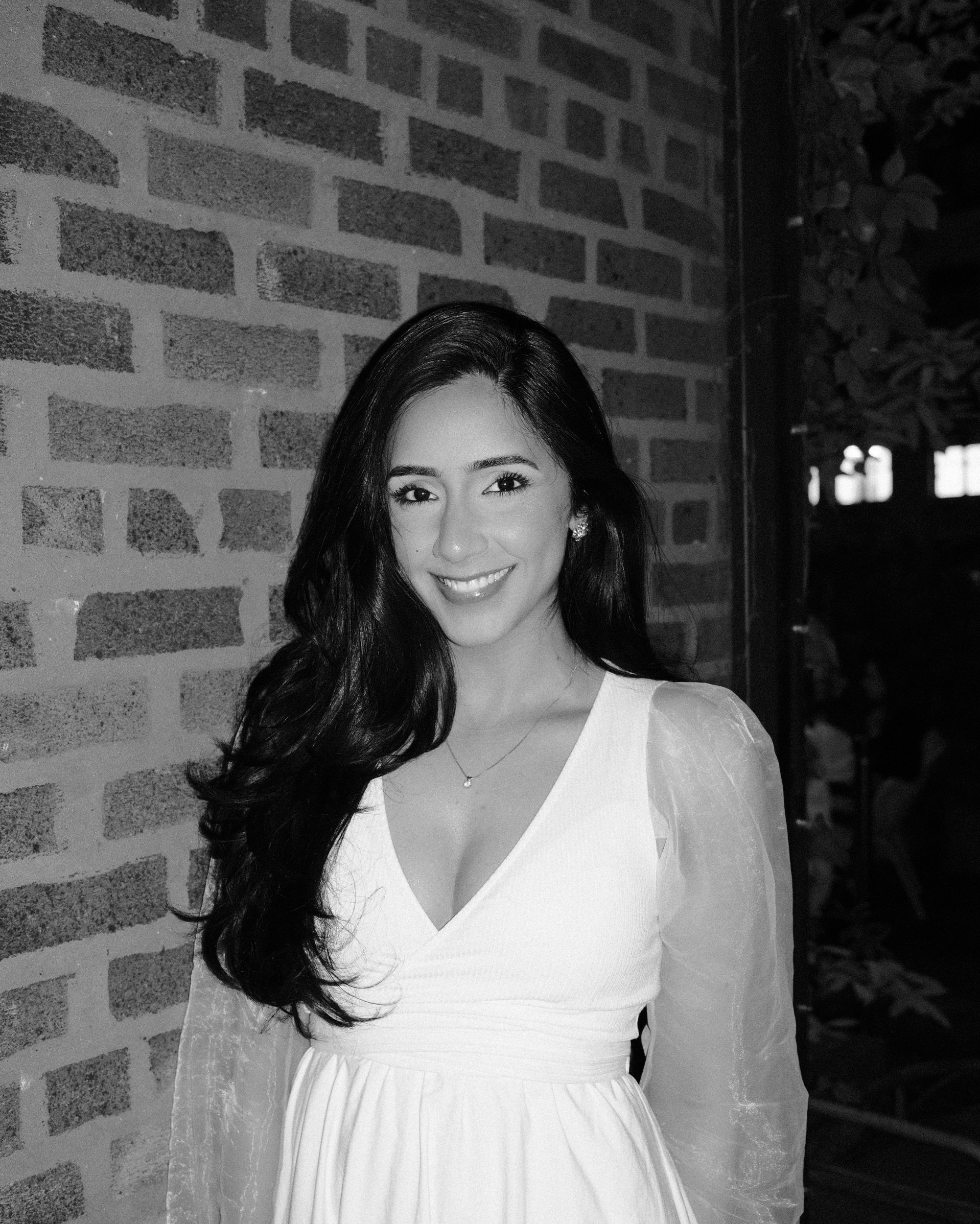 Black and white portrait beside a brick wall