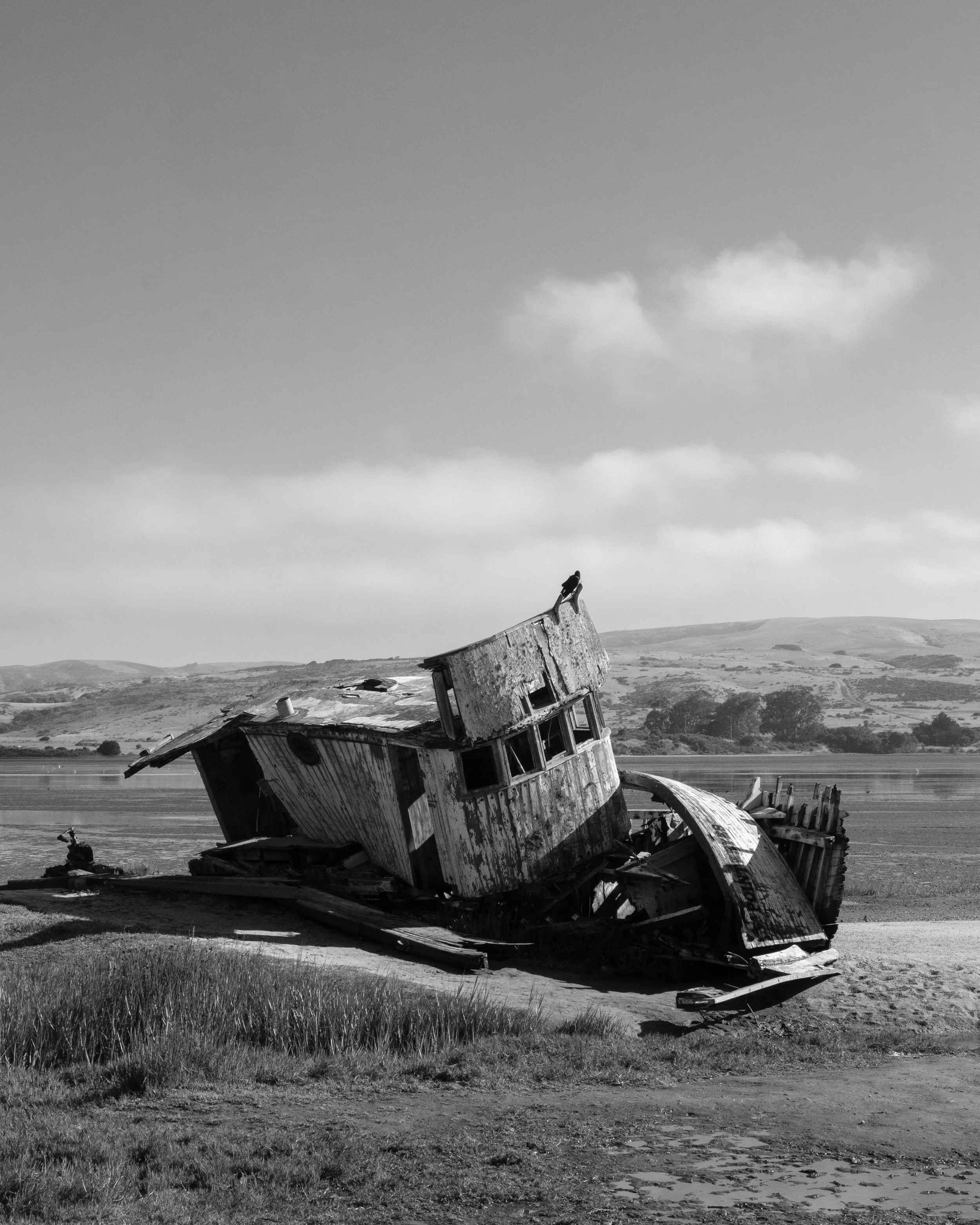 Weathered boat beside calm water and distant hills