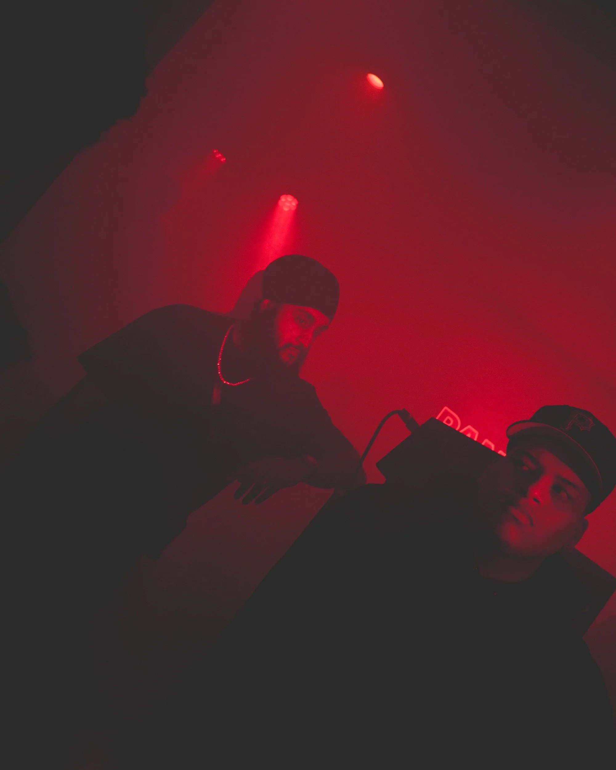 Performers beneath red lighting at a music event