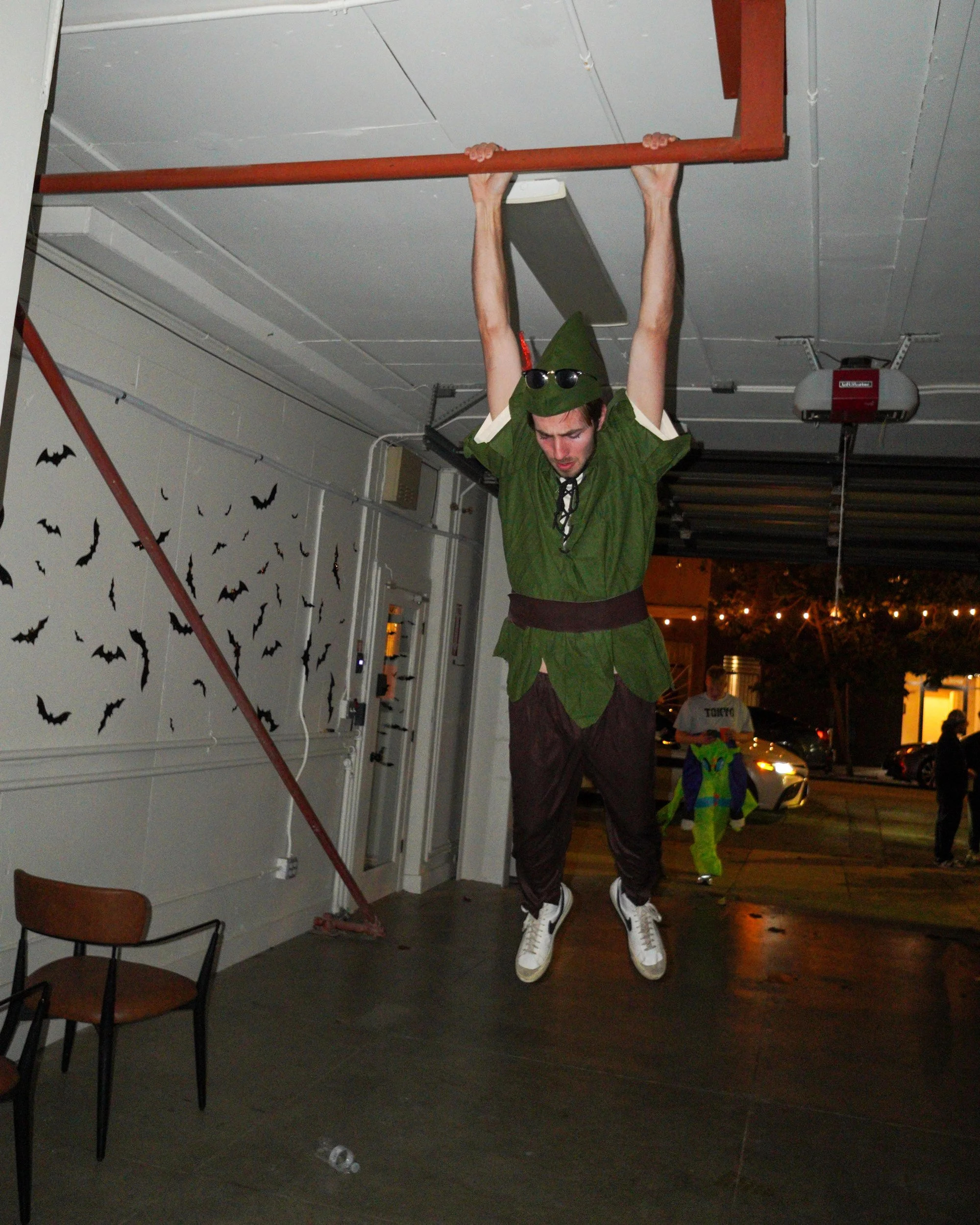 Costumed guest hanging from a bar at a Halloween party