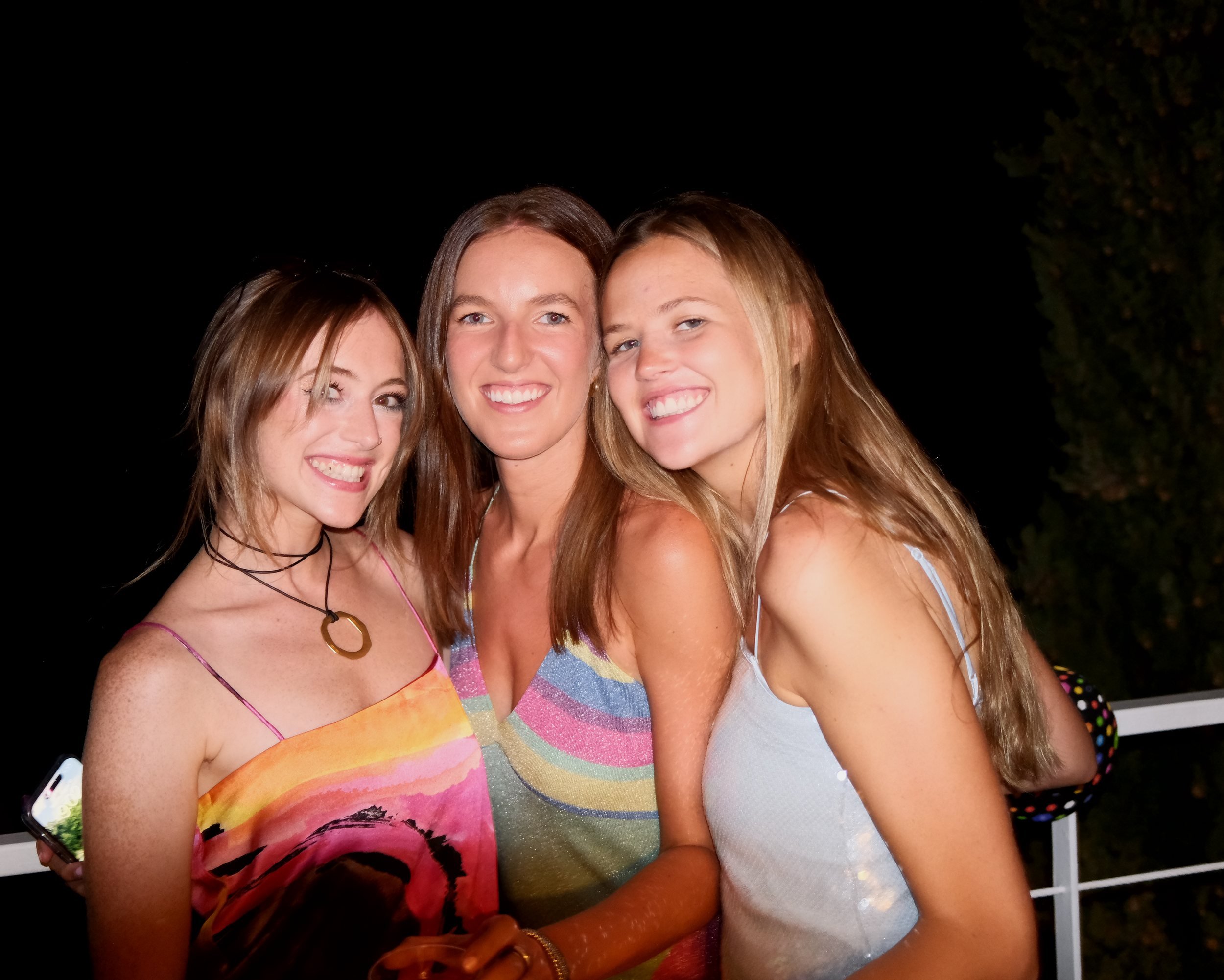 Three friends smiling at an evening gathering