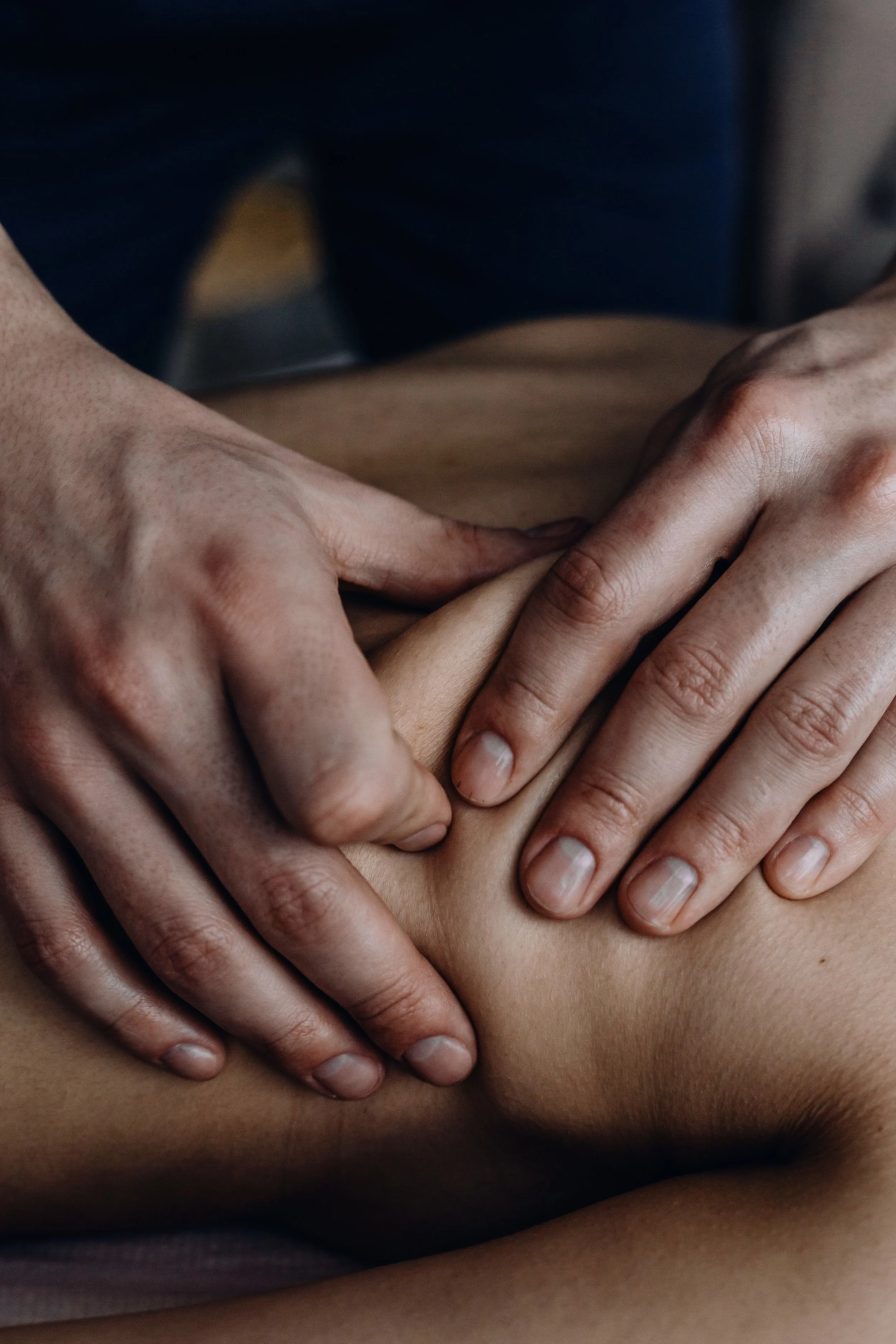 Close-up of multiple hands pressing on a person's back, providing a massage.