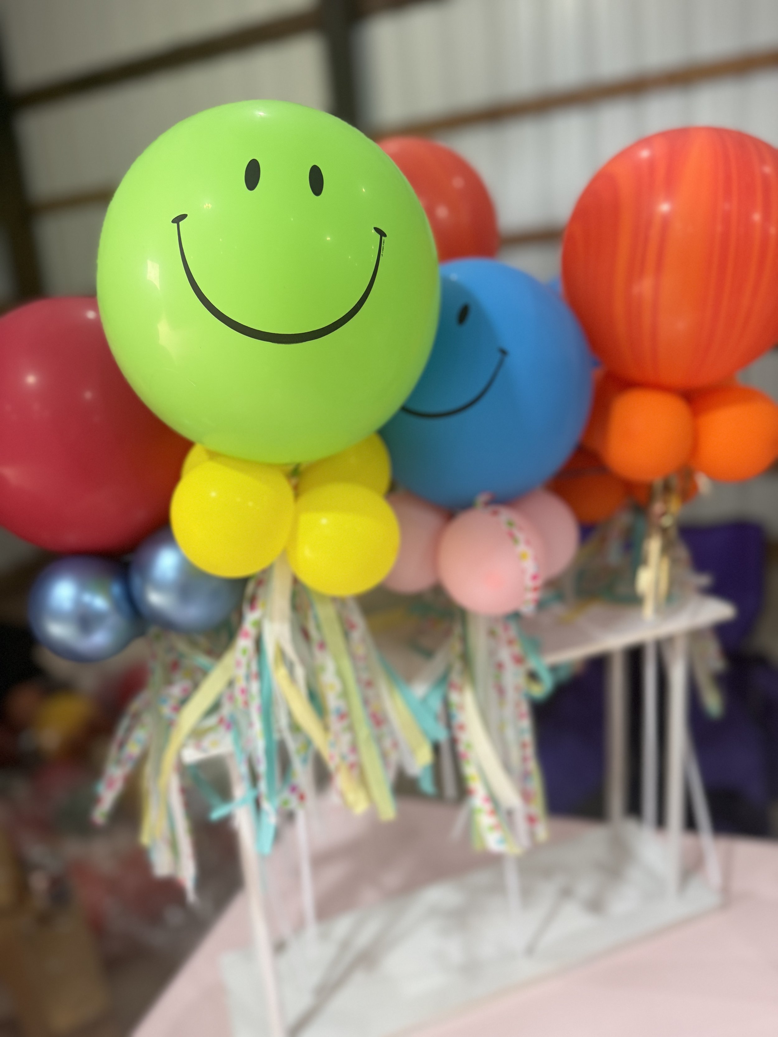 Colorful balloons with smiling face designs on them, arranged in a display.
