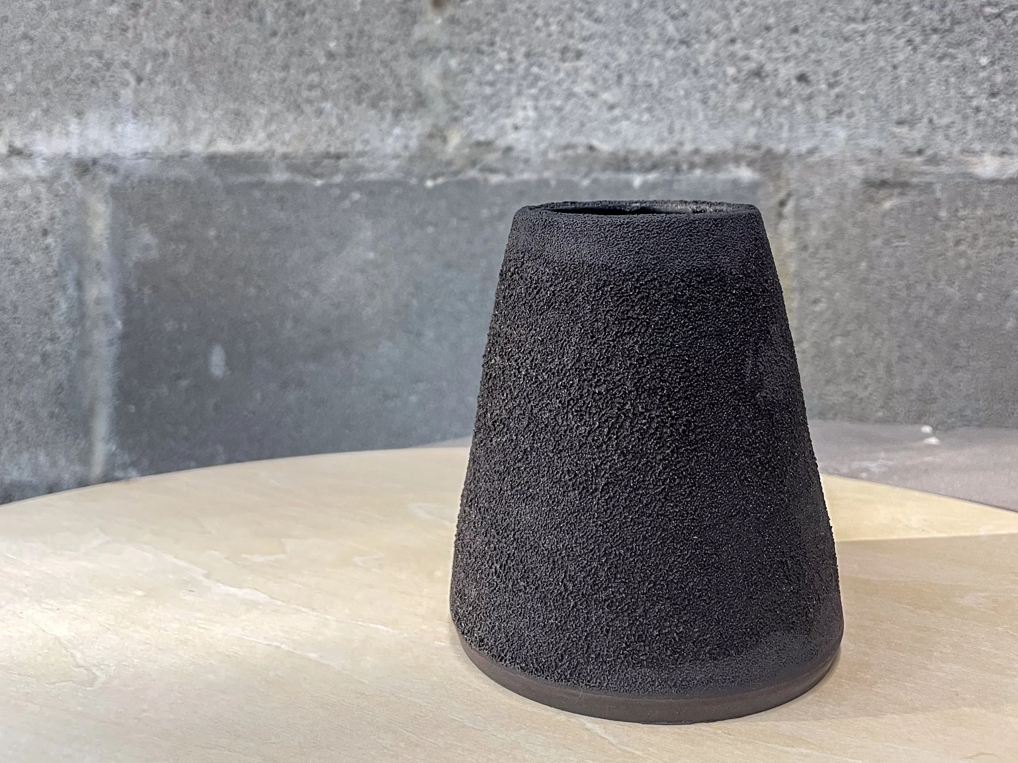 wheel-thrown stoneware flower vase in dark textured glaze, stark minimal form, Auburn Alabama