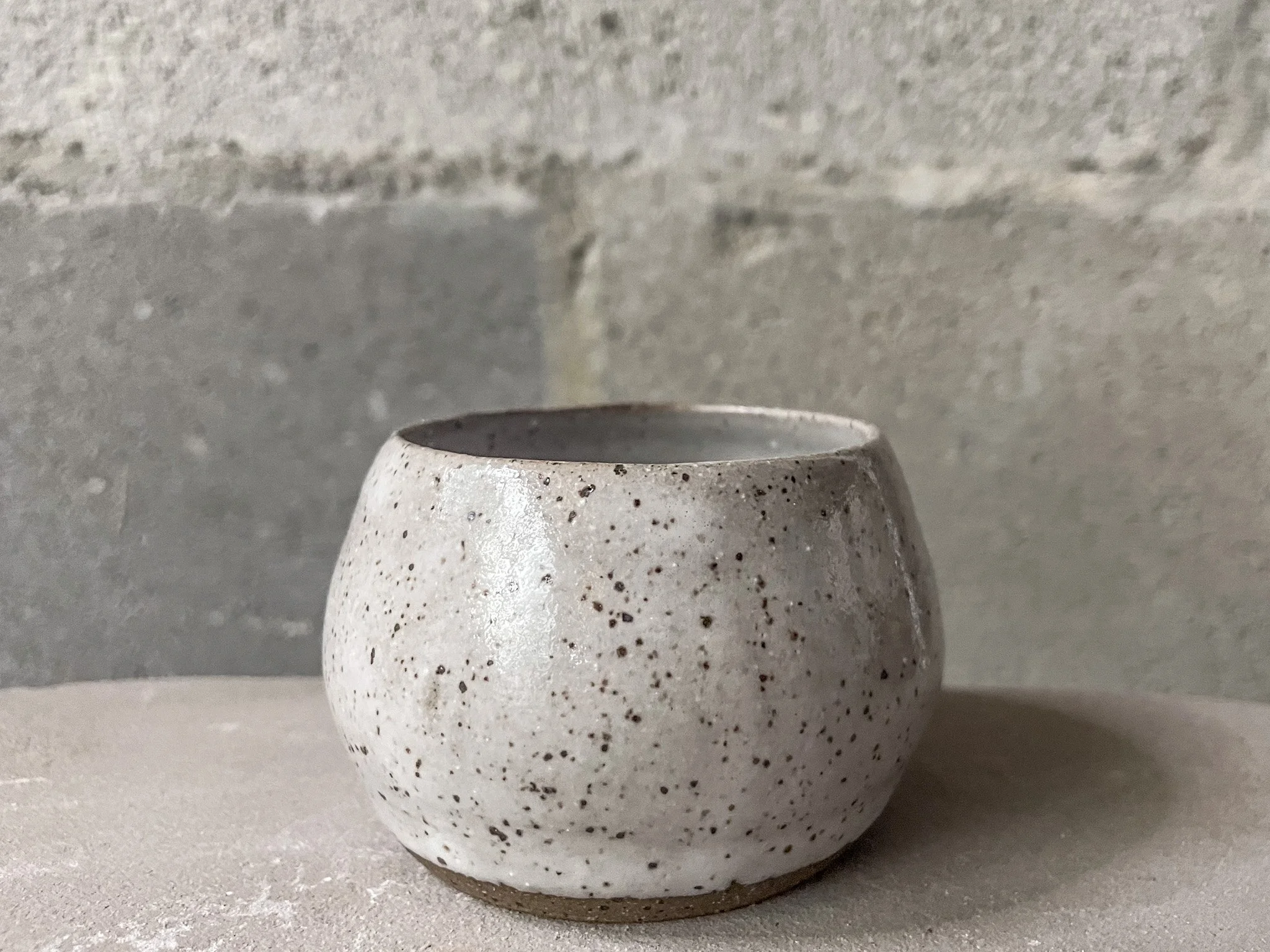 wheel-thrown stoneware cup in glossy white glaze, brutalist minimal form