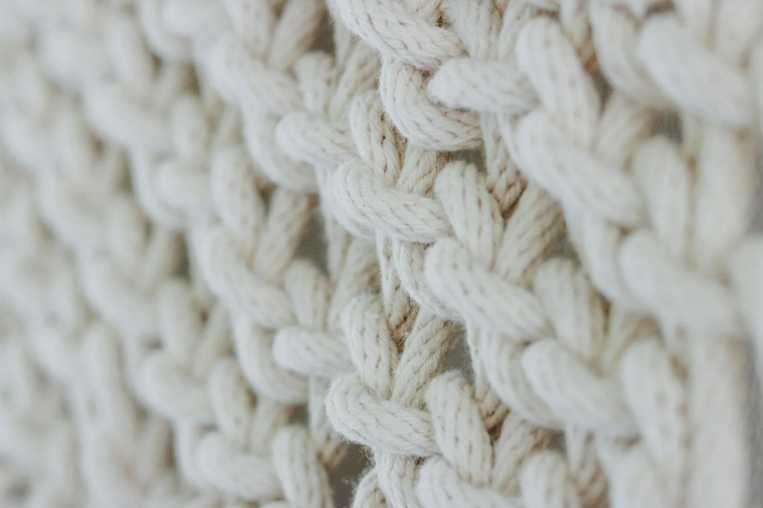 Close-up of cream-colored, woven rope yarn creating a textured pattern.