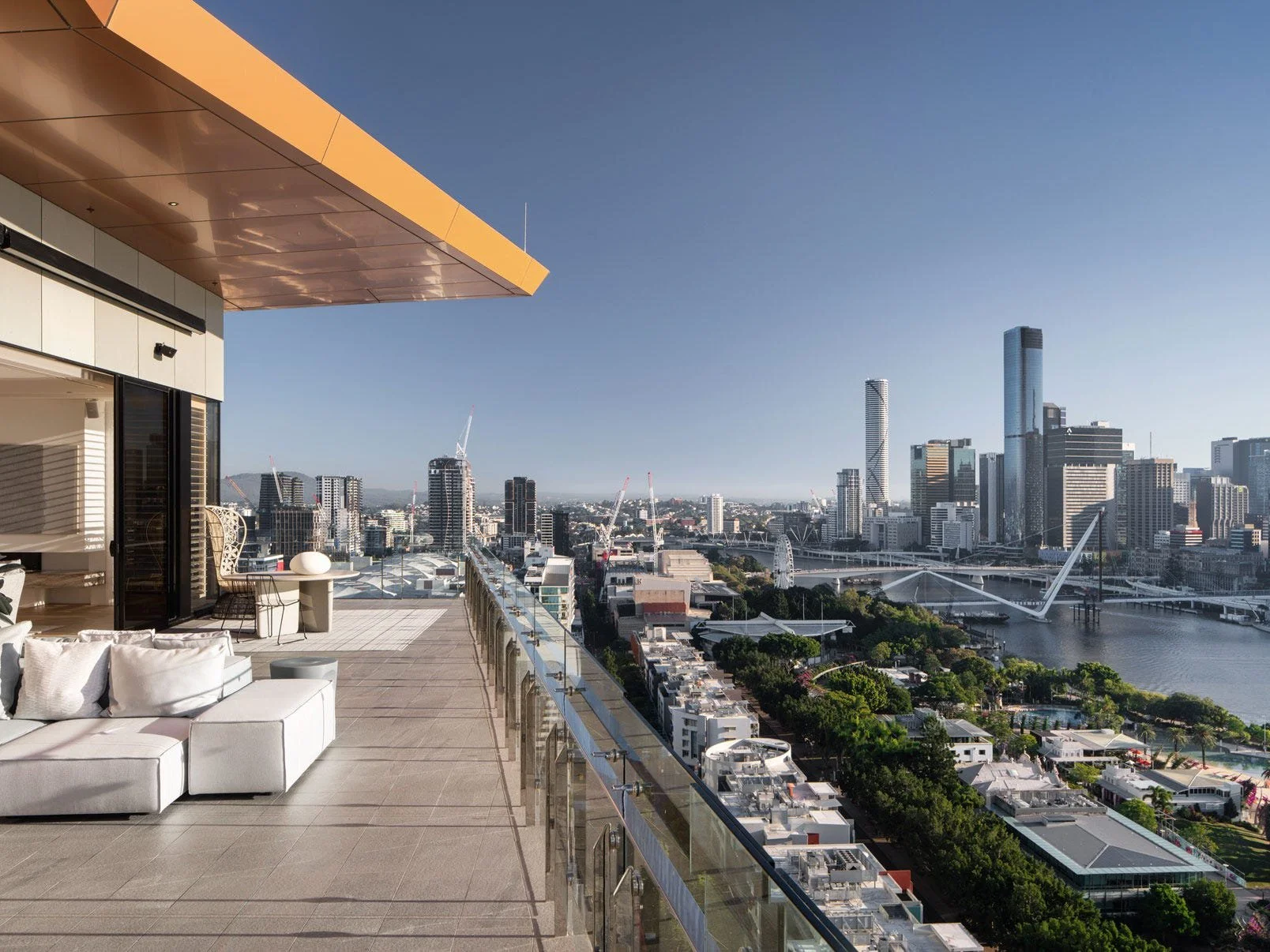 Modern rooftop terrace with outdoor seating overlooking a city skyline with tall buildings and a river.