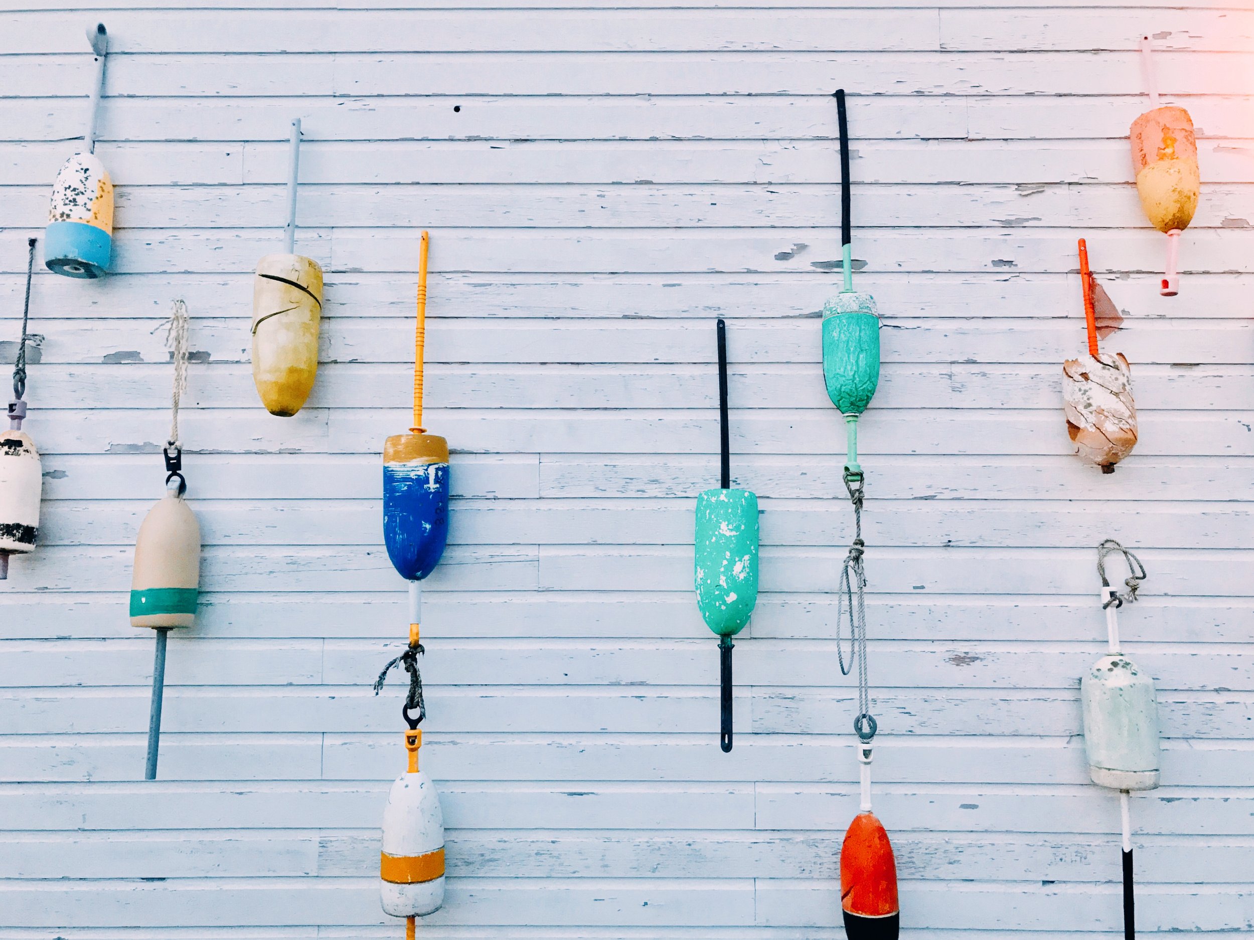 Colorful fishing buoys hanging on a white wooden wall.