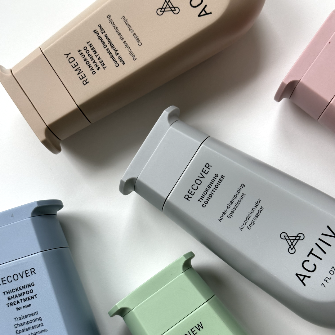 Arranged bottles of hair care products, including thickening shampoo, conditioner, and treatment, in pastel colors on a white surface.