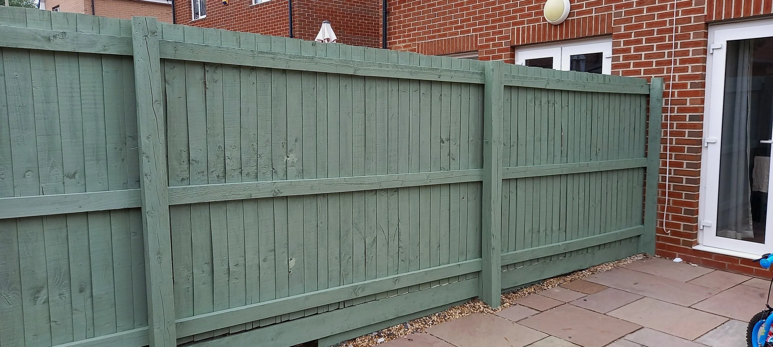 A previous dull brown fence brightened up with a fresh coat of green paint.