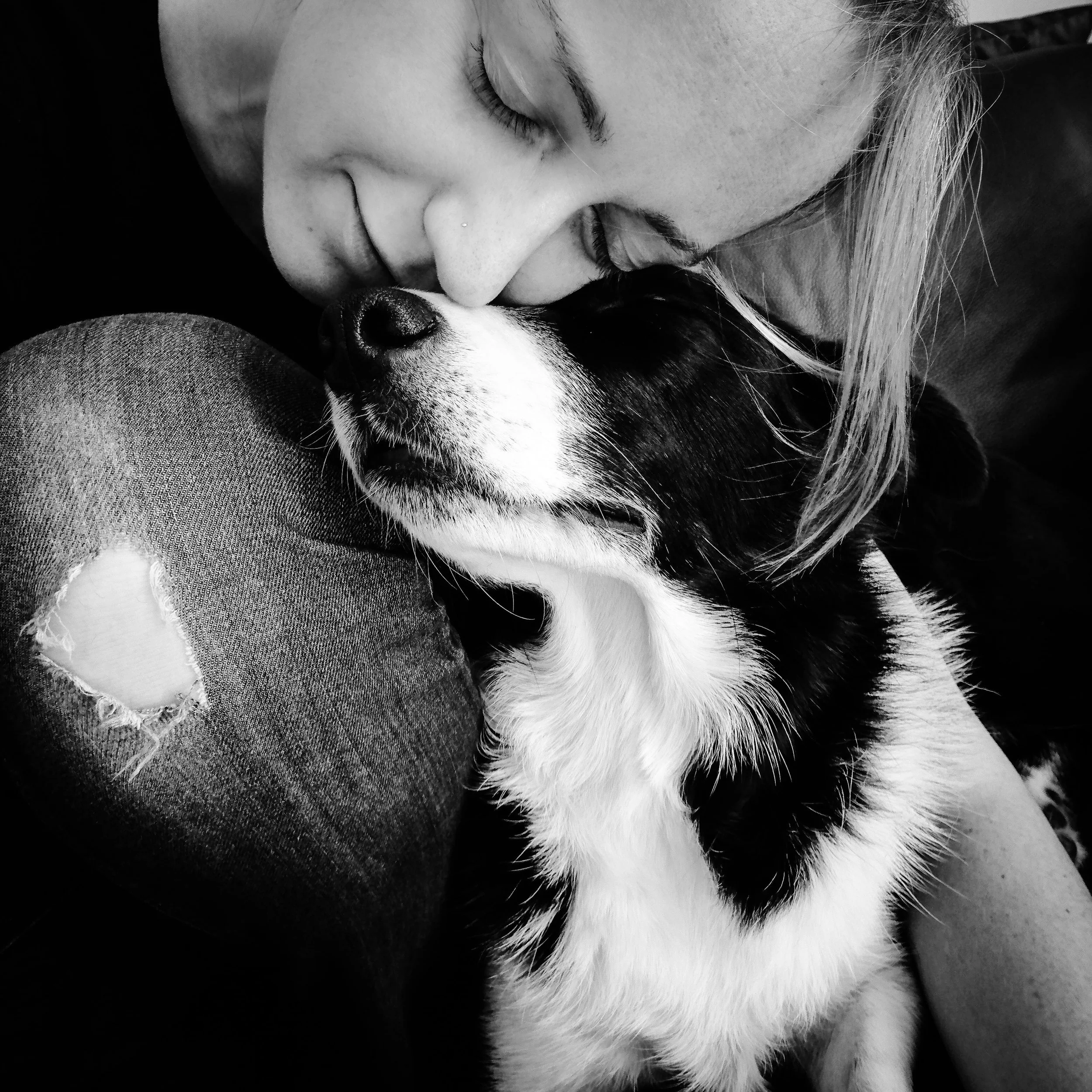 Een vrouw die haar ogen dichtknijpt en een Border Collie dieknuffelt.