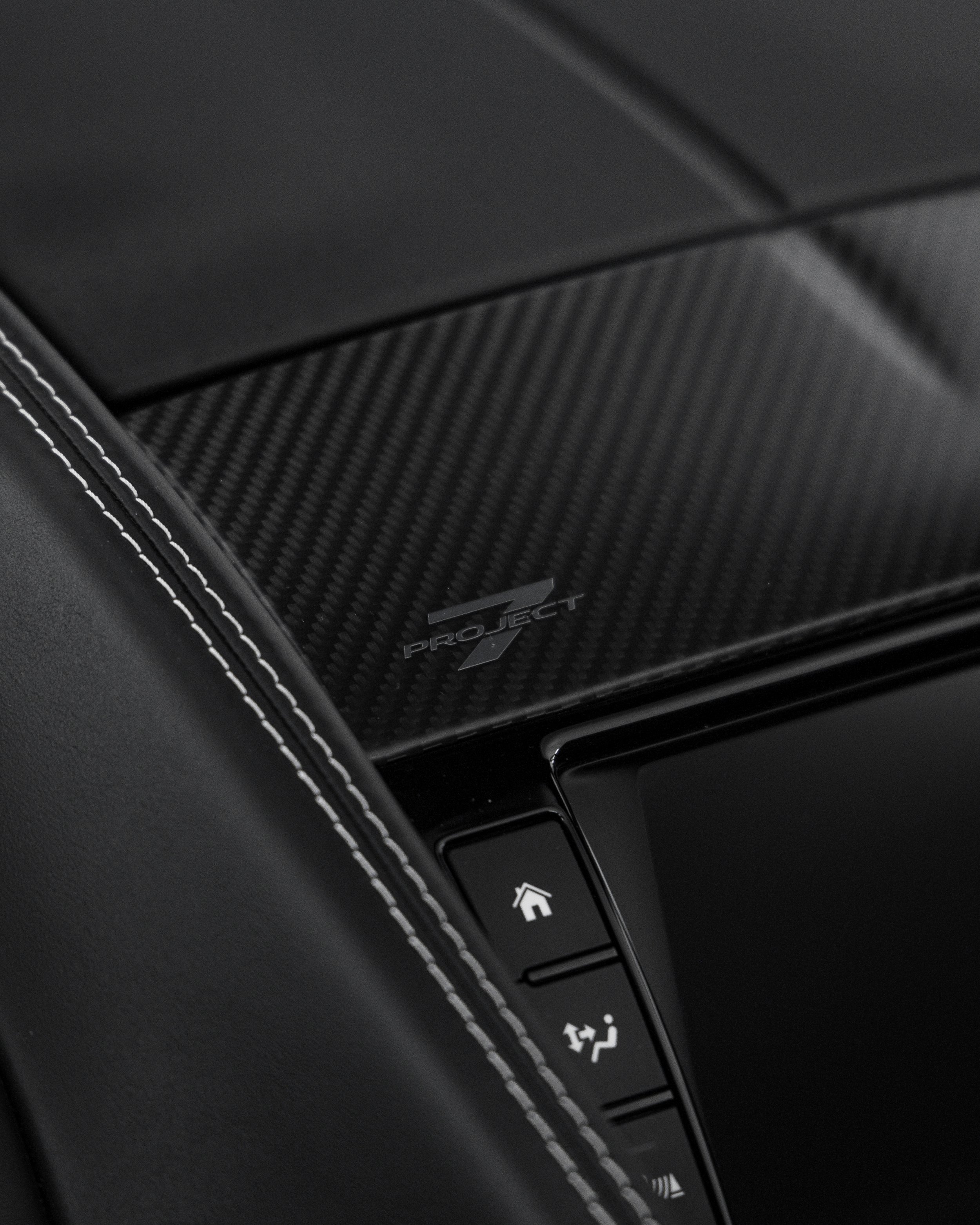 Close-up of a car interior showing a textured dashboard with Project 7 logo and a curved control panel with house and traffic icons.