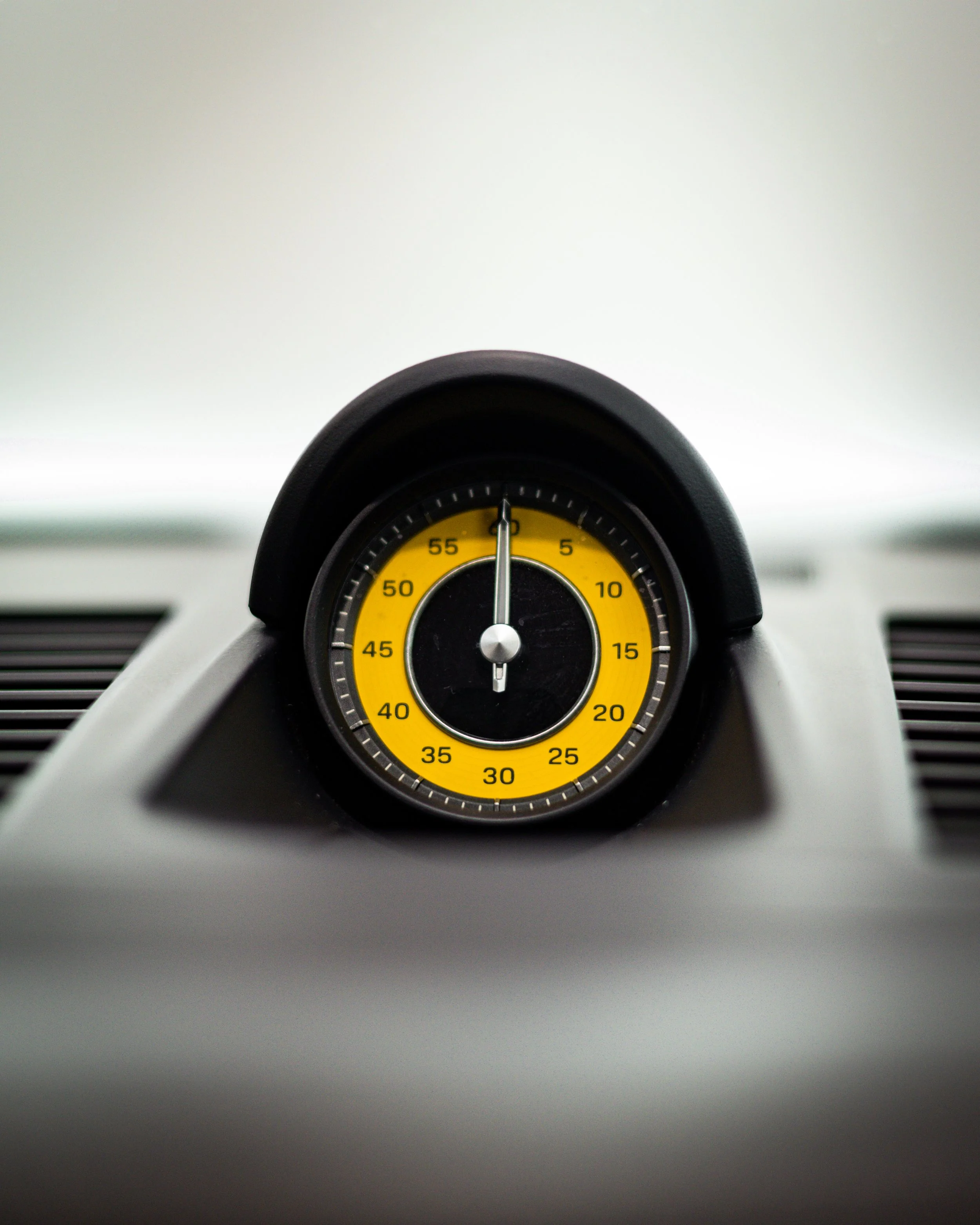 A close-up of a car dashboard stopwatch with a yellow and black face showing 60 seconds.