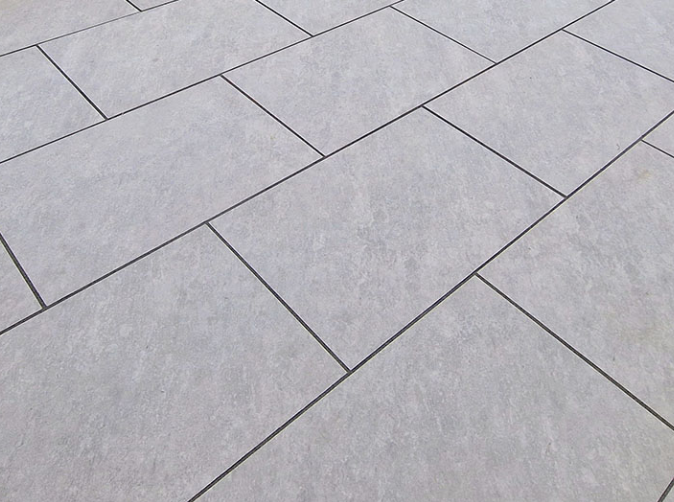 Close-up of light gray tiled floor with black grout lines.
