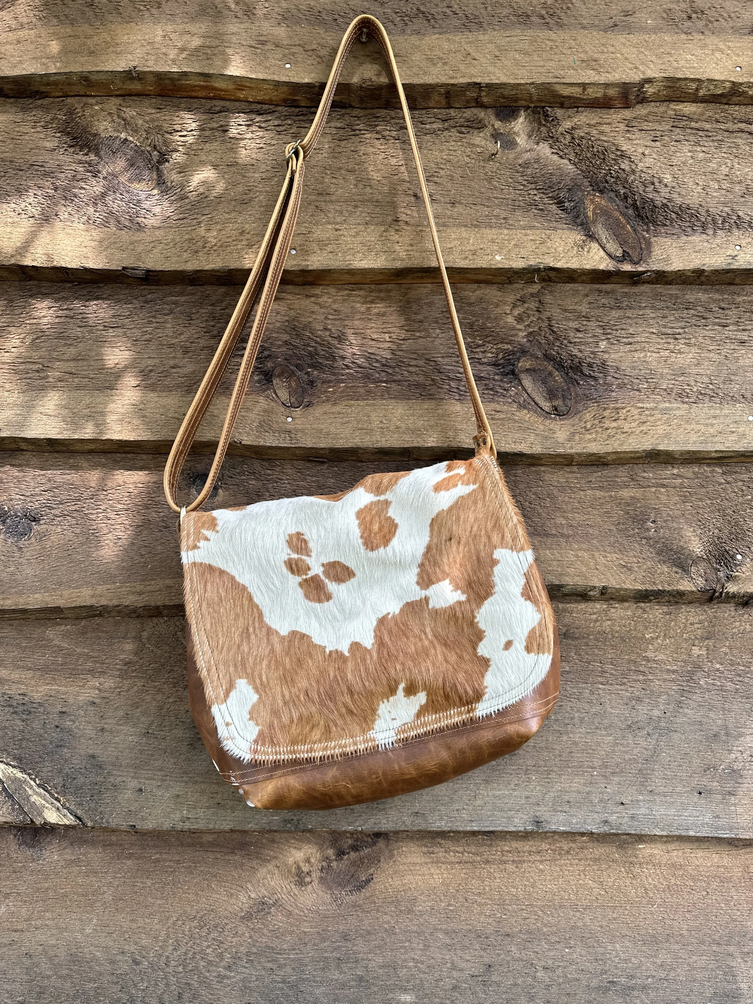 Brown and white cowhide-patterned Eustis hanging on a wooden wall.