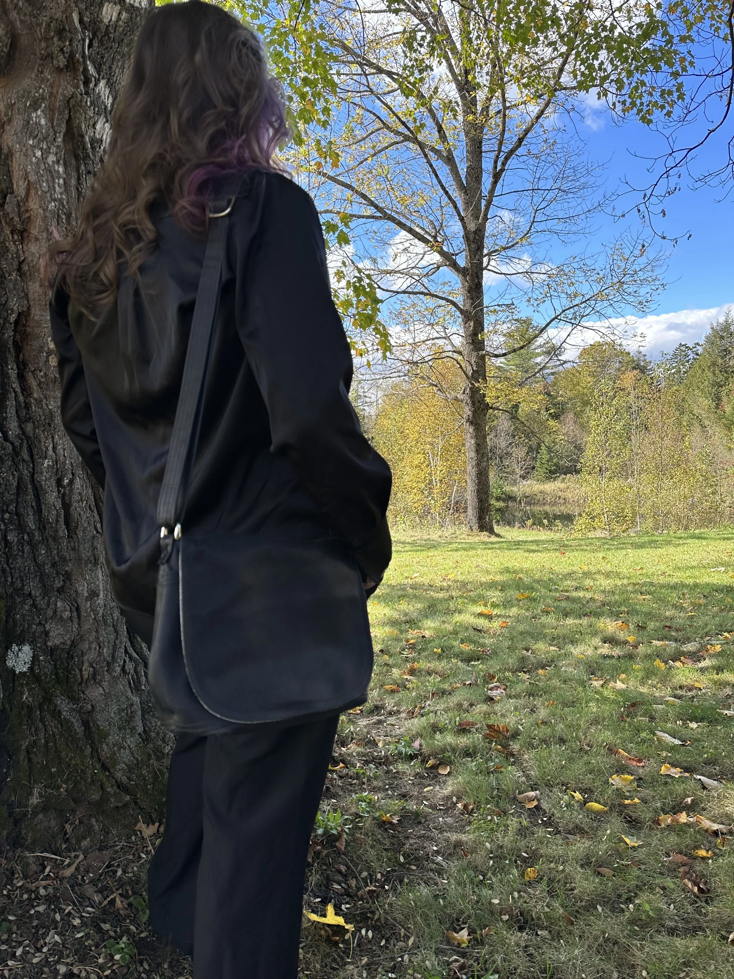 Jennifer in all black with a beautiful black Eustis saddlebag on her shoulder, looking off in the distance.  ATCo. offer timeless leather handbags that prioritize craftsmanship over trends.