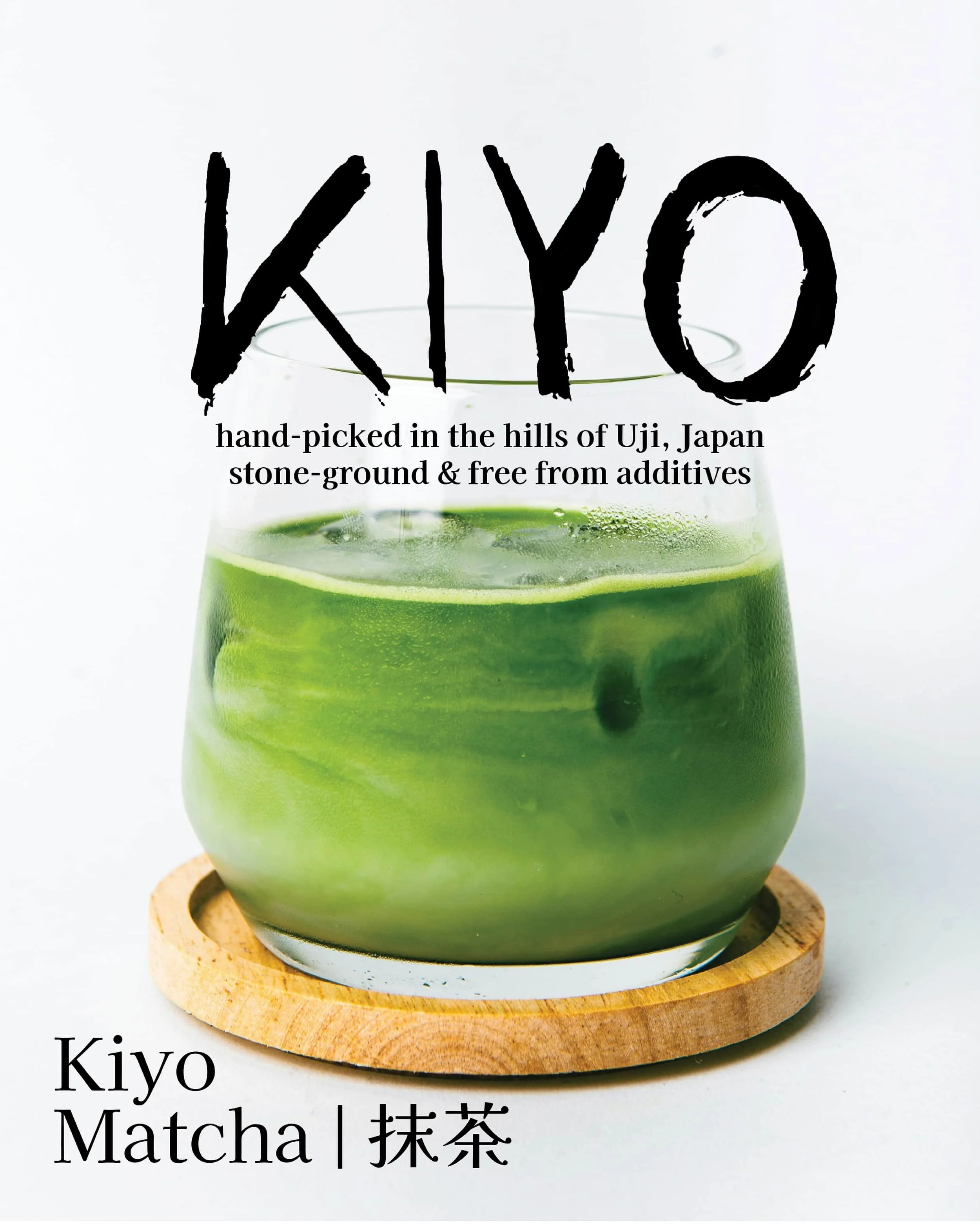A glass of green matcha tea on a wooden coaster with text overlay promoting Kiyo Matcha, hand-picked in Japan, stone-ground, and free from additives.