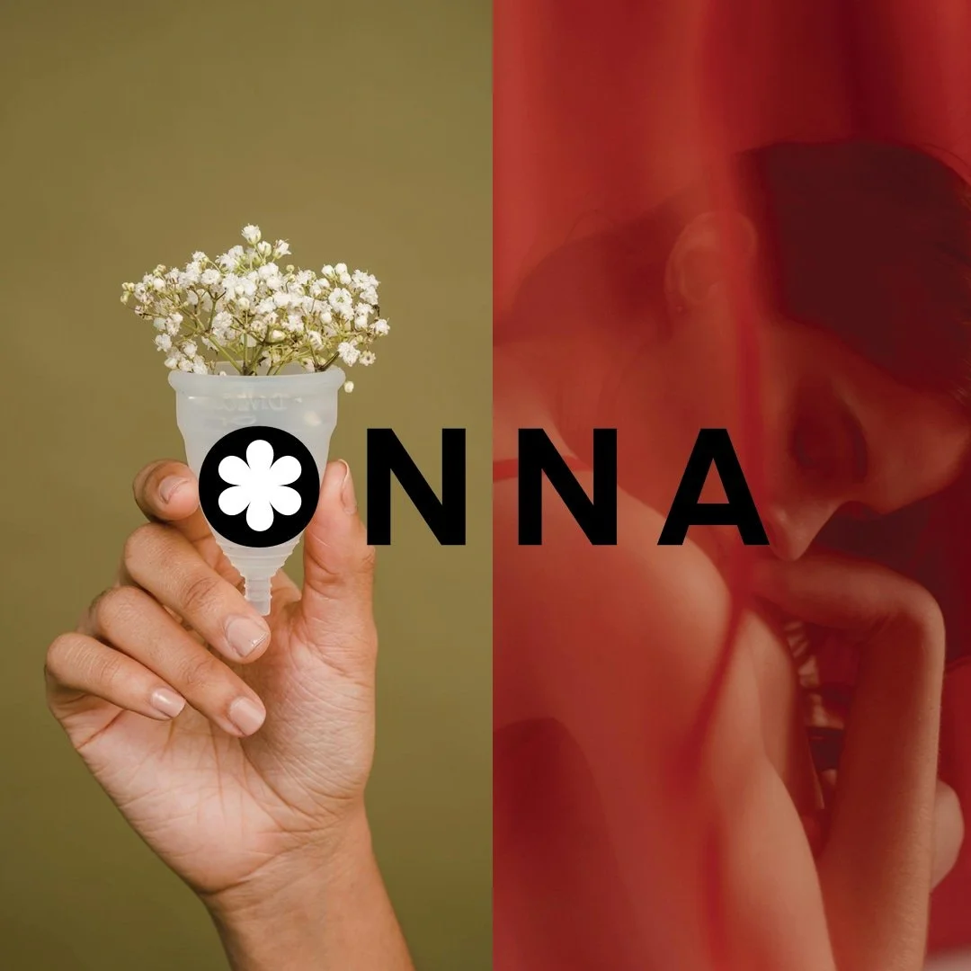 A hand holding a white flowerpot with white flowers and the word 'ONNA' written across the middle, fitting with an artistic photo of a person with reddish lighting and a contemplative expression.
