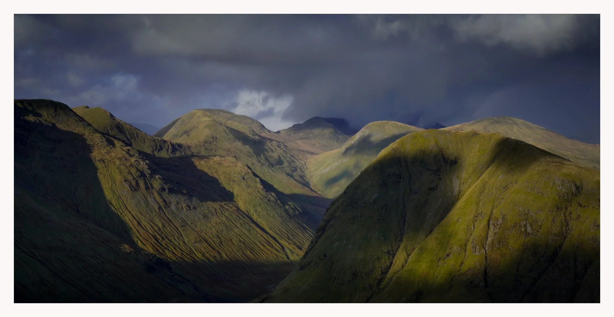 Green mountains under dark stormy clouds.