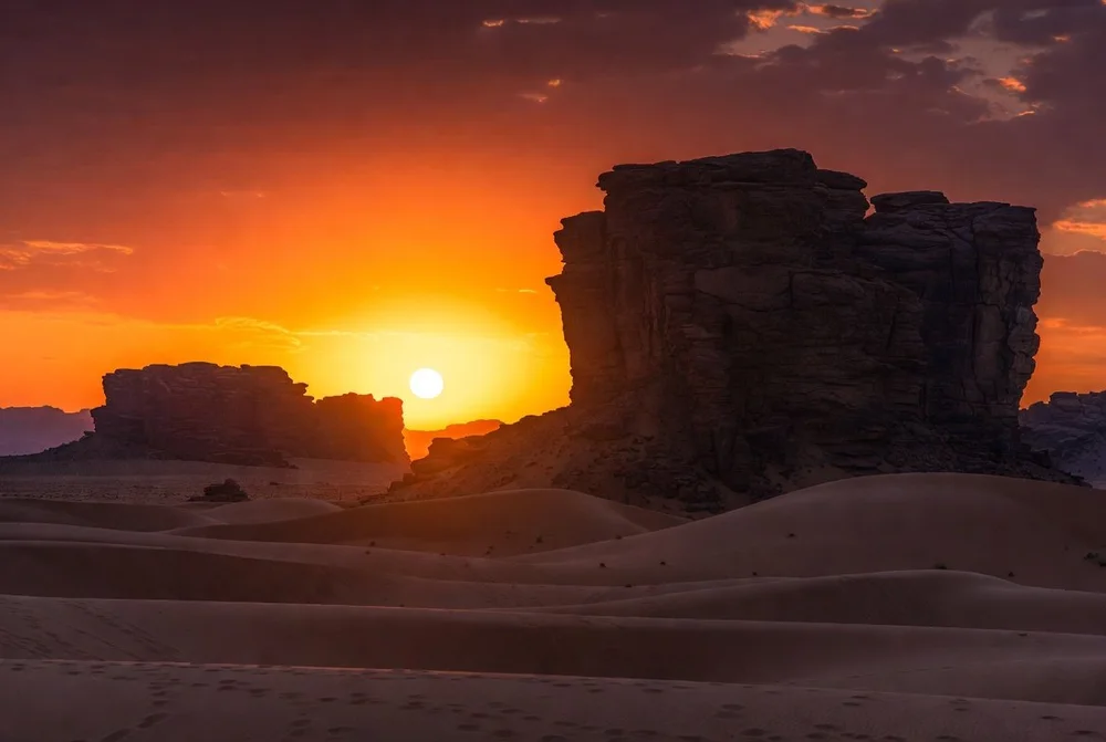 Massifs rocheux et dunes au coucher de soleil près de Djanet