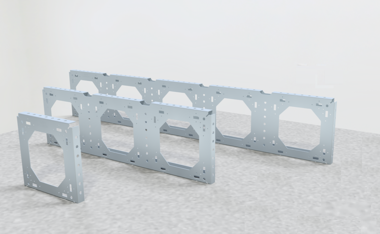 Three steel single plate elements with hexagonal openings, arranged in two rows on a light gray speckled floor against a white wall.
