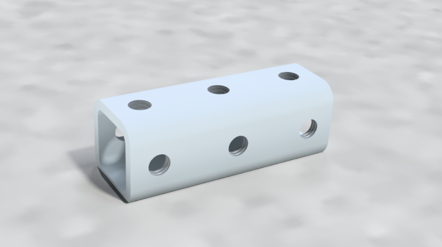 A metallic piece with multiple threaded holes lying on a light-colored surface.