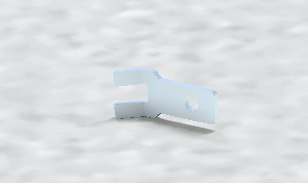 A small, metallic, silver-colored wrench with a hole in the middle, lying on a white, textured surface.