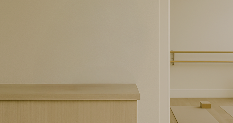 Minimalist room with a wooden bench and ballet barres on the wall.