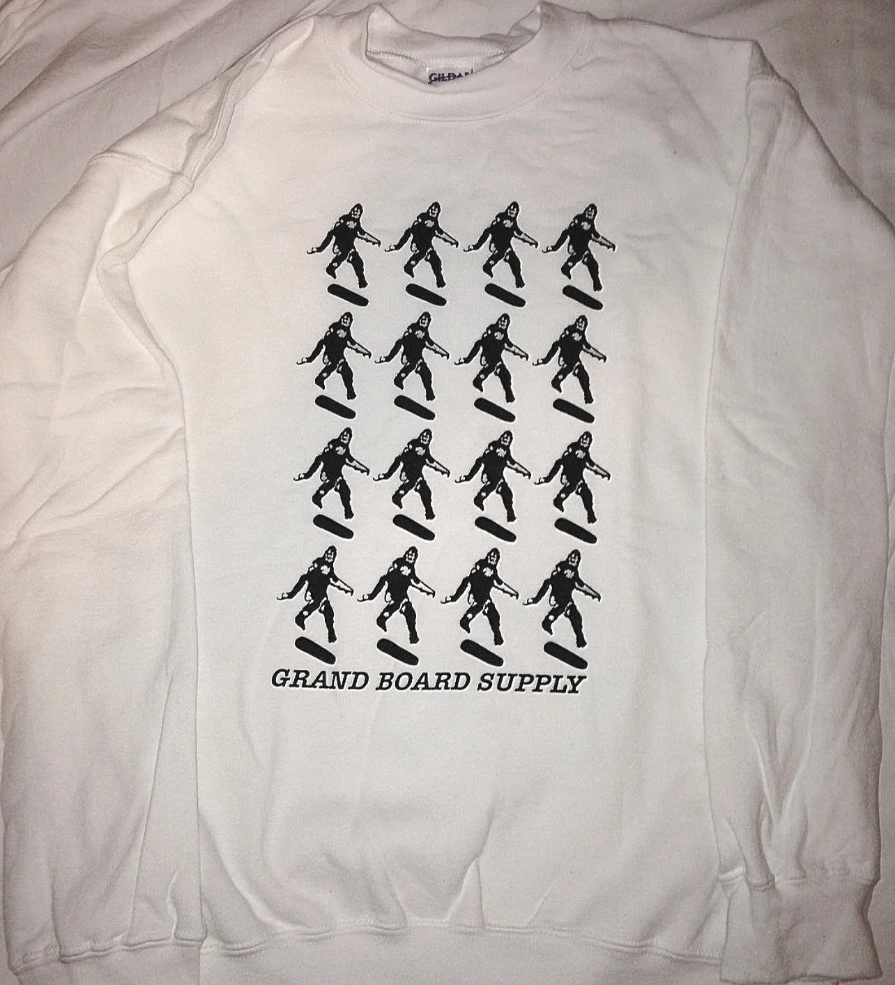 White sweatshirt with a black graphic depicting multiple skateboarders in various skateboarding stances and the text 'Grand Board Supply' at the bottom.