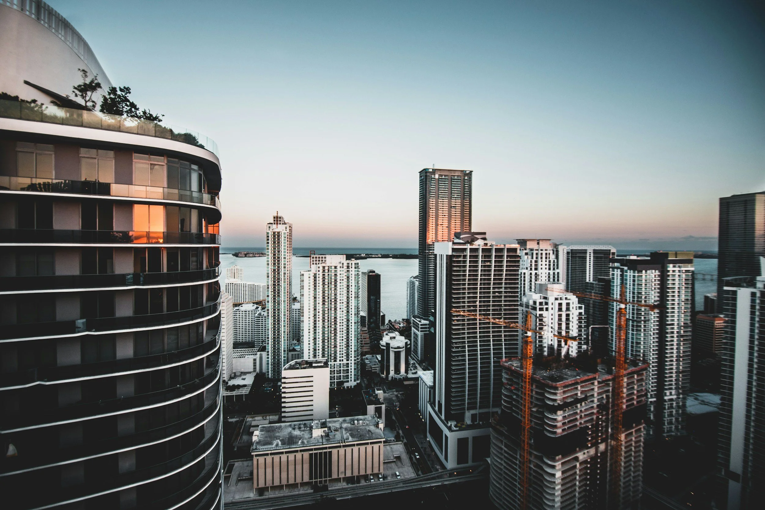 City skyline at sunset with high-rise buildings and water in the background.