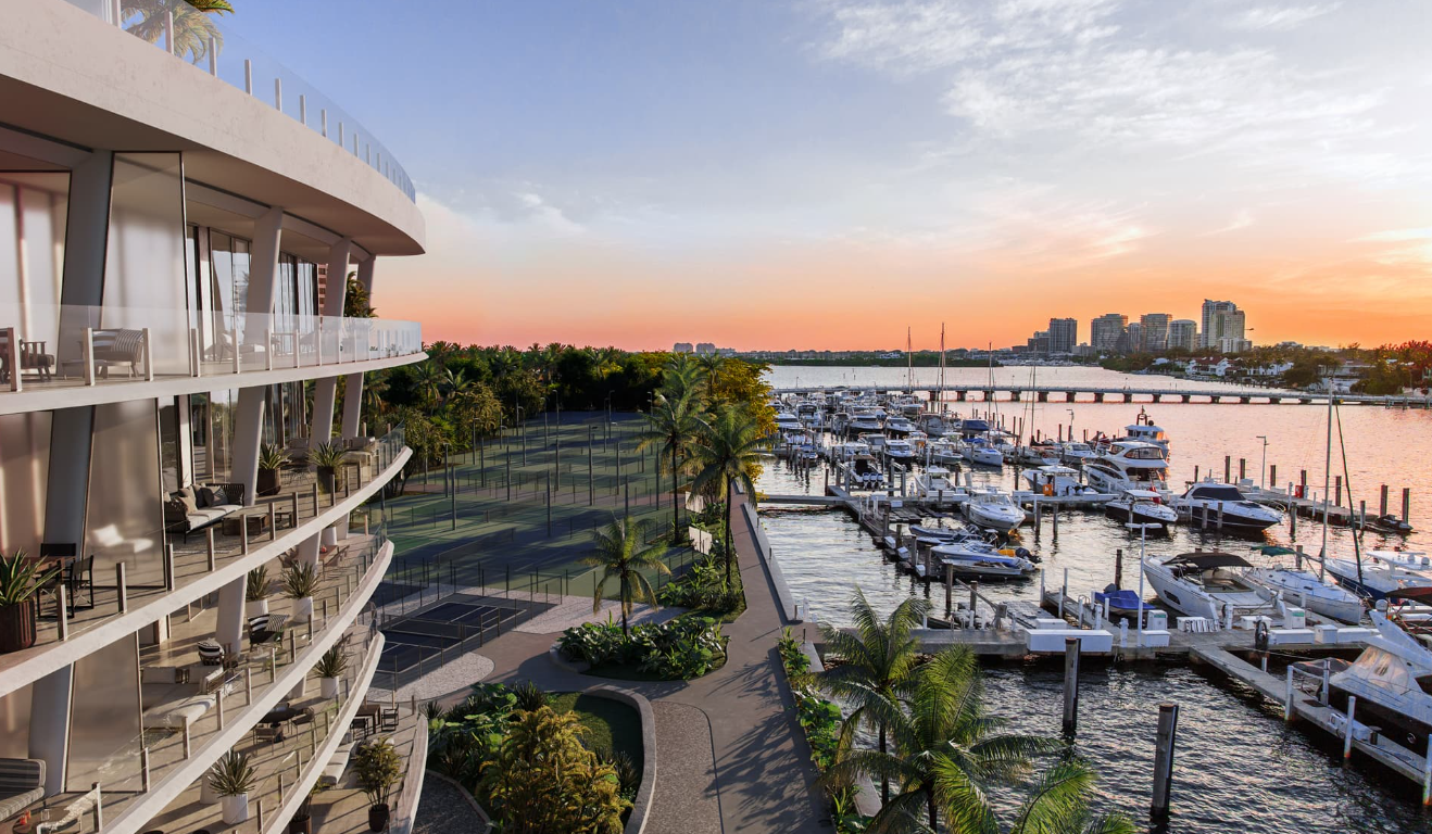Vacation resort with balconies overlooking a marina full of boats at sunset, with buildings in the background.